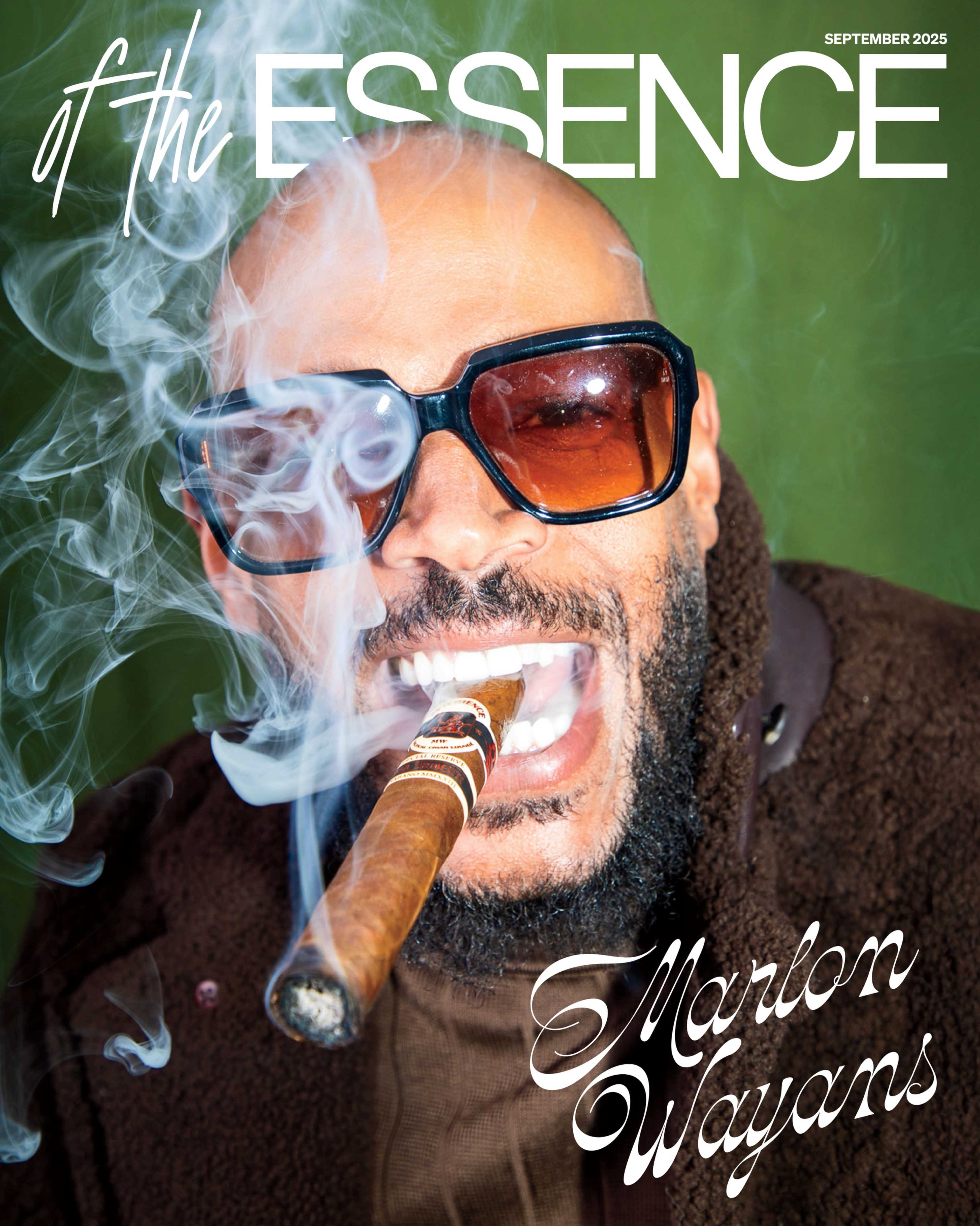 A man with sunglasses smirks while holding a cigar, surrounded by a cloud of smoke against a green backdrop.