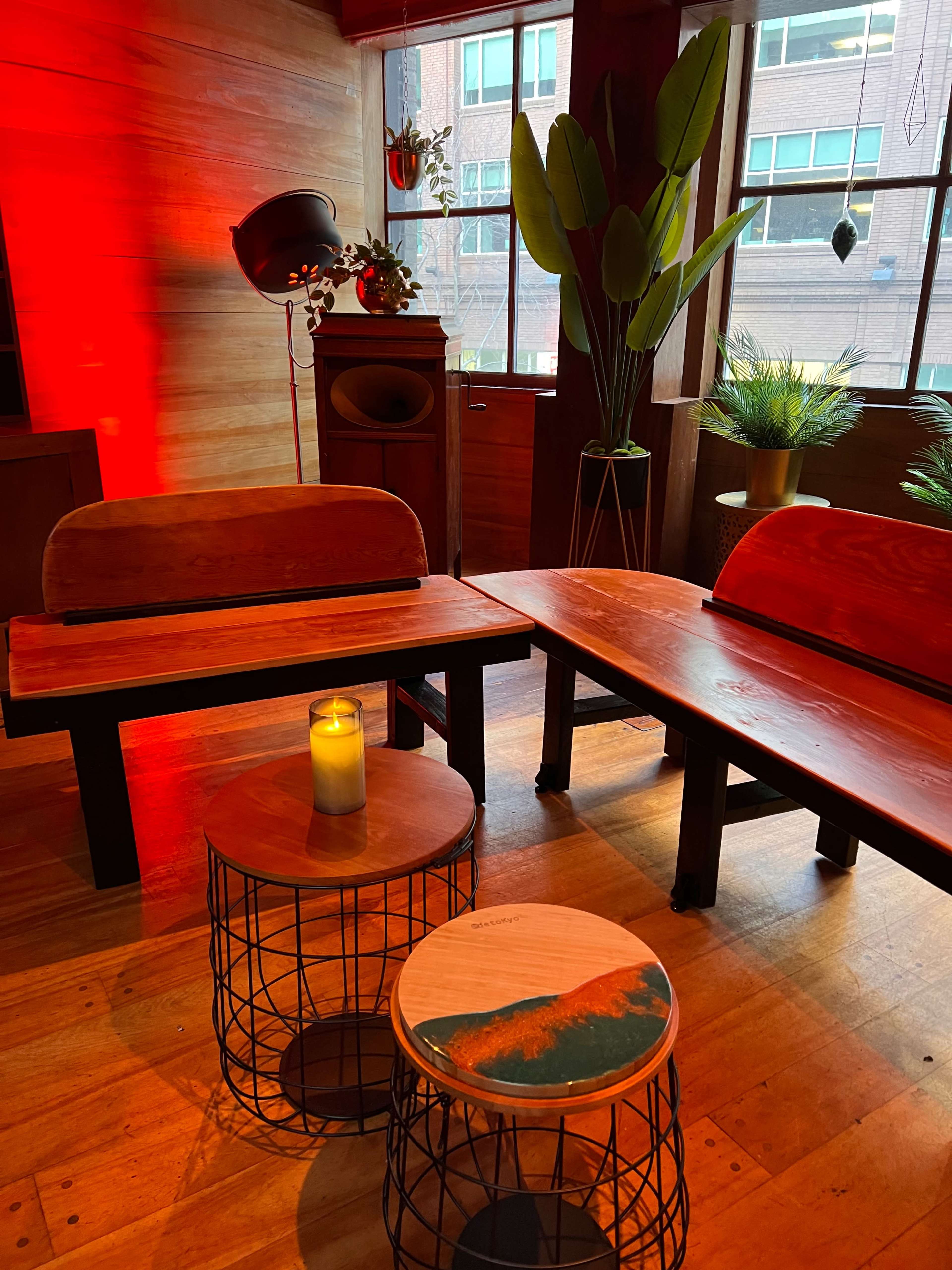A cozy, modern interior featuring wooden seating, metal-accented side tables, and decorative plants.