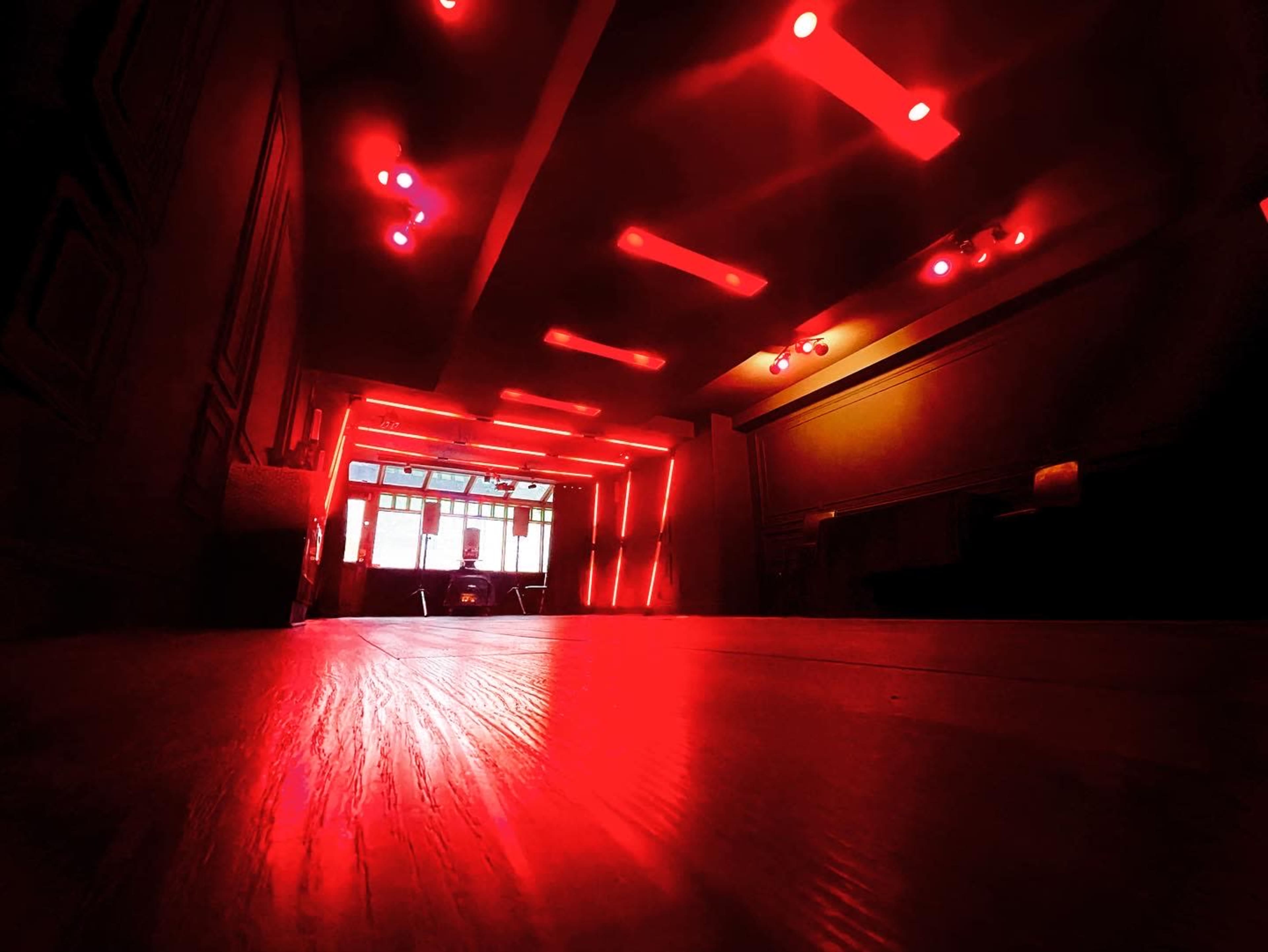 A dimly lit room with red LED lights and a wooden floor.