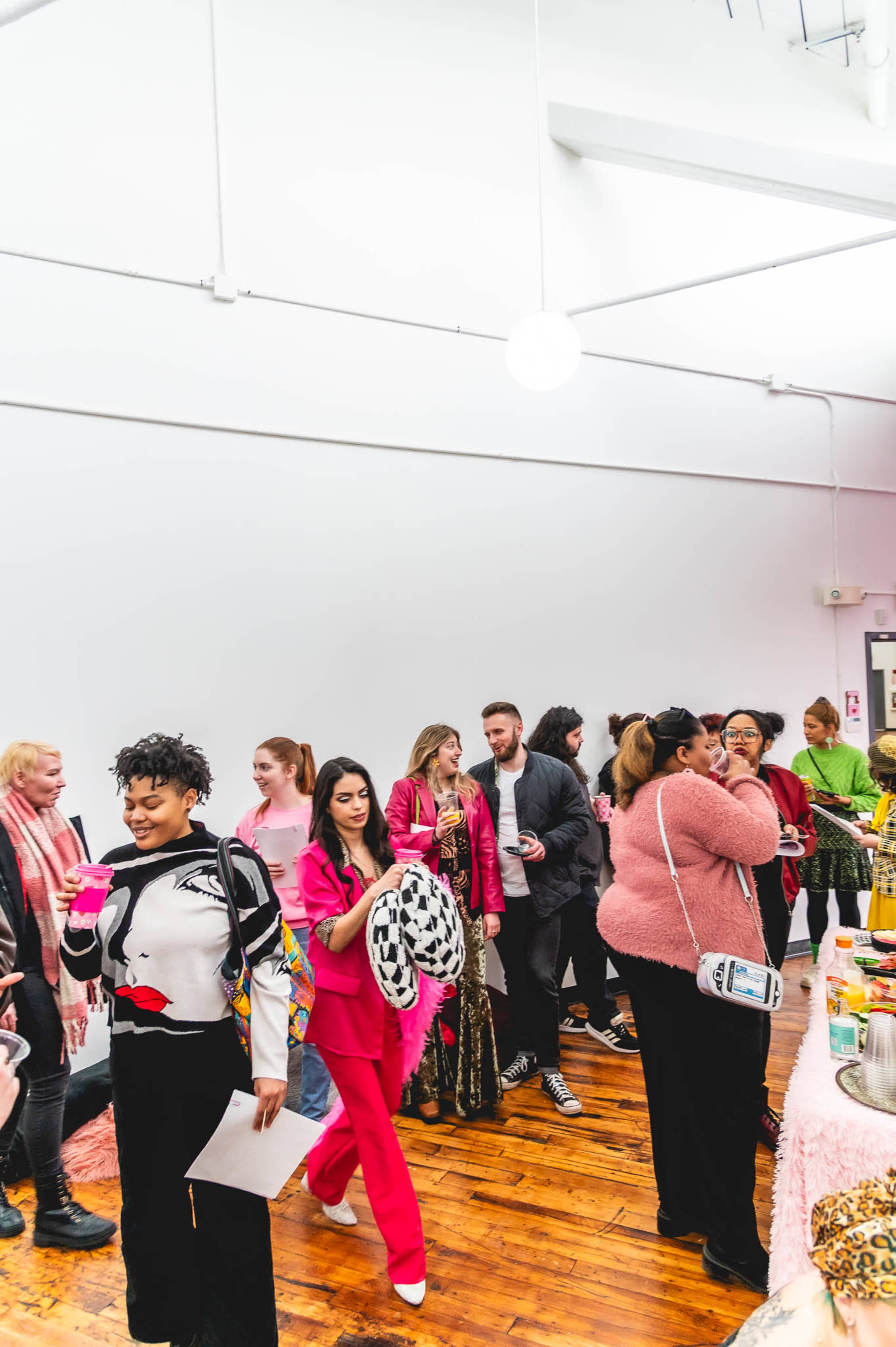 A diverse group of people socialize and enjoy refreshments at a brightly lit indoor event.