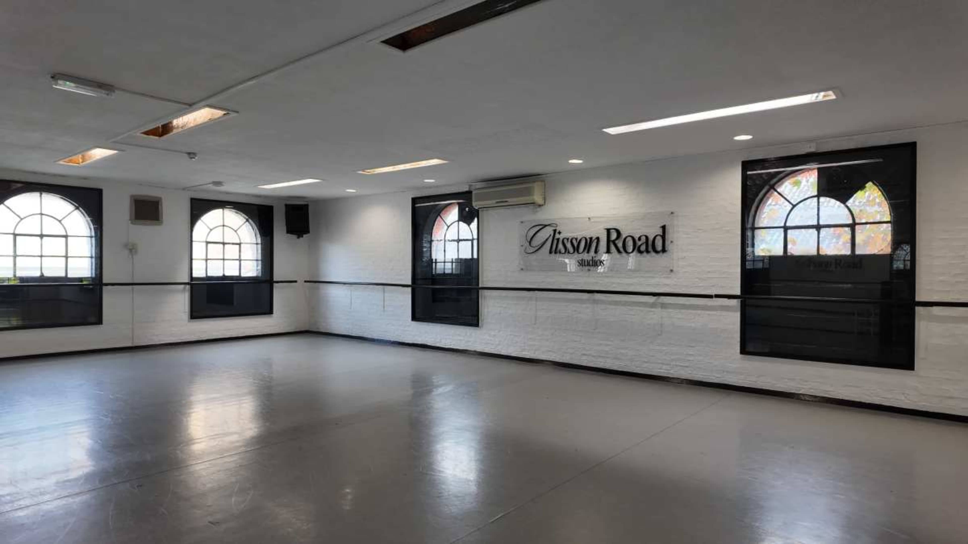 The image shows a spacious, well-lit studio or room with large windows, featuring the name "Gisson Road" on the wall.