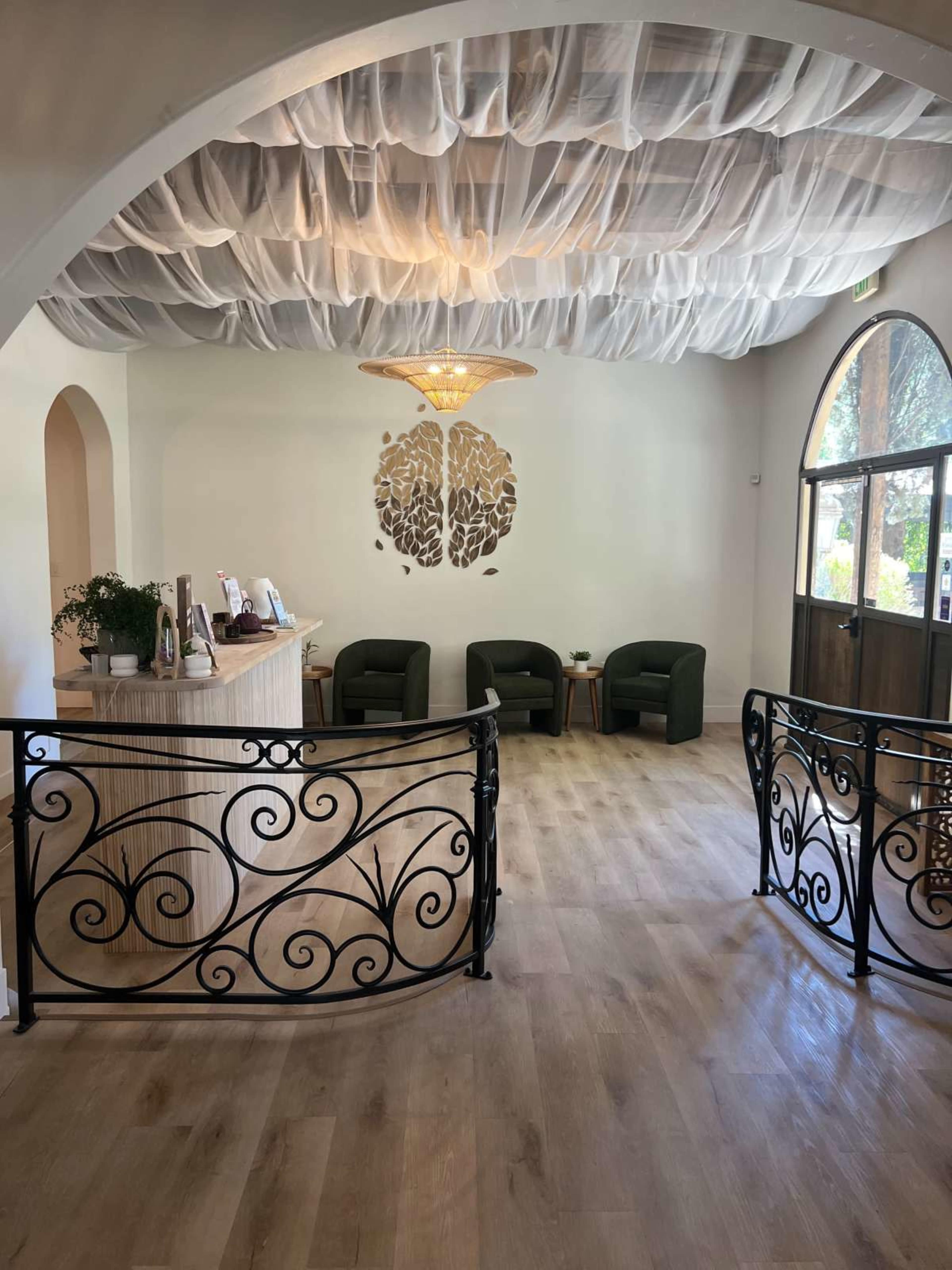 A lobby area with a curved counter, green chairs, and a decorative ceiling covered in fabric.