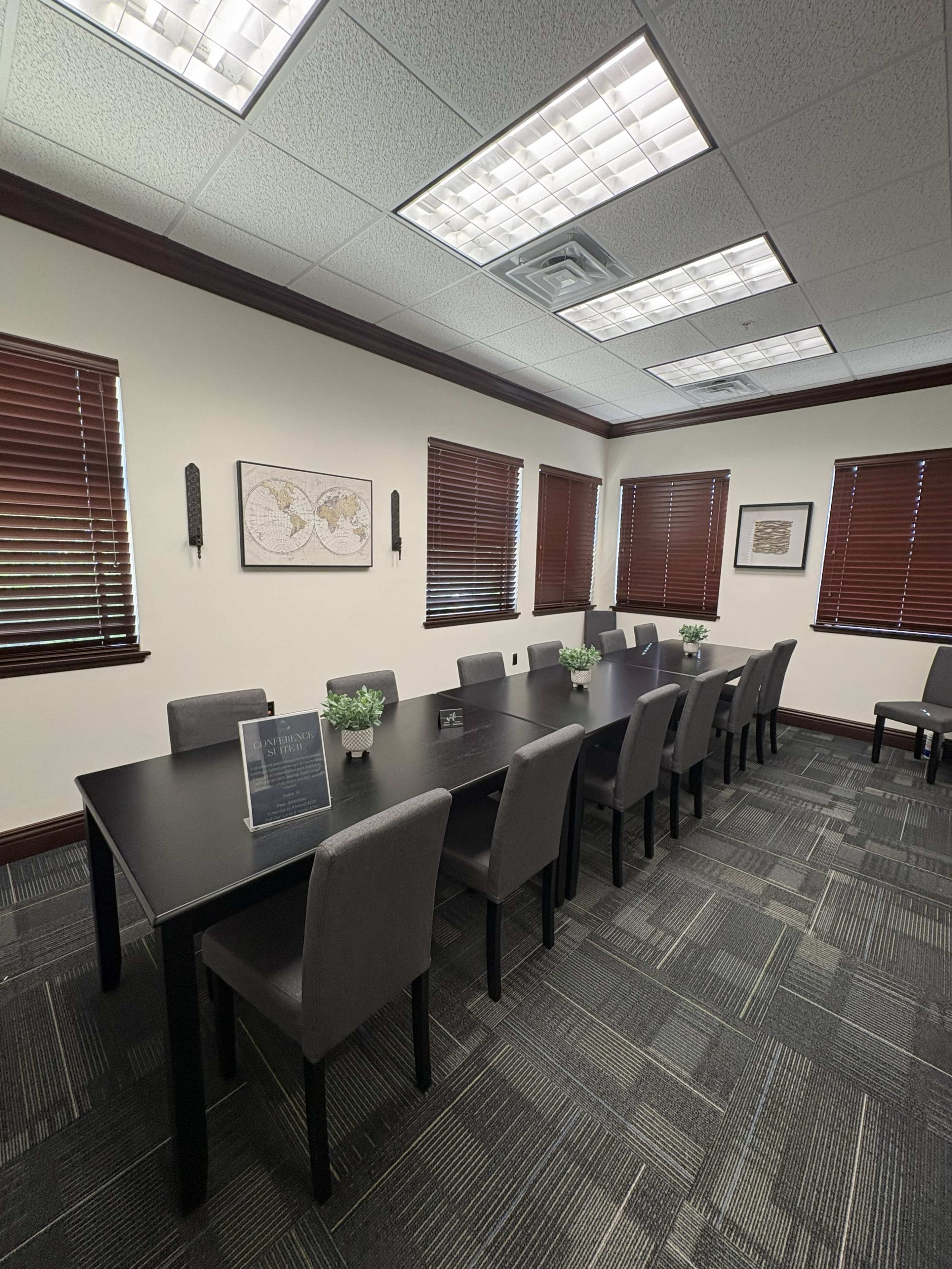 The image shows a modern conference room with a large rectangular table, chairs, and wall-mounted art pieces.
