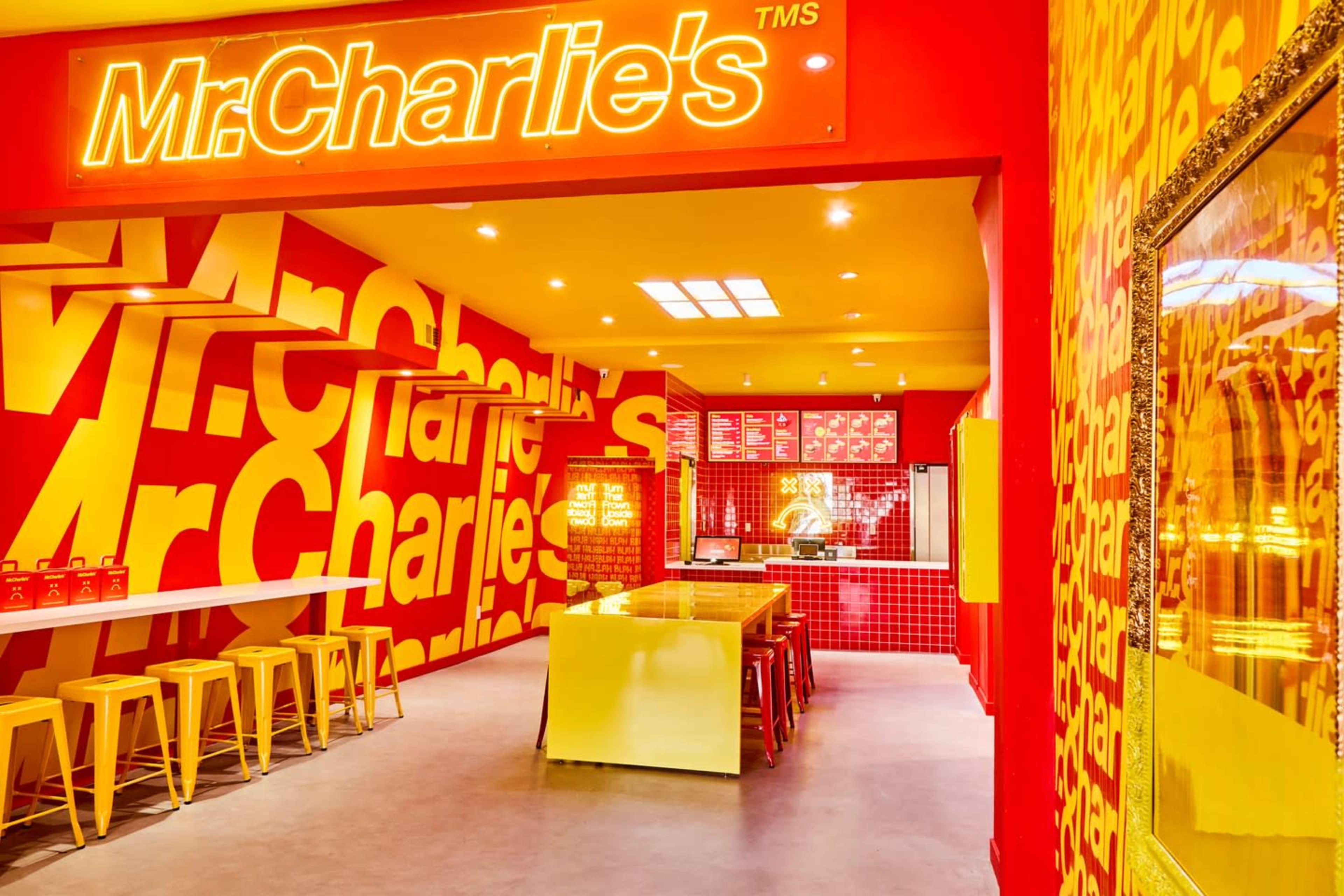 The image shows the interior of a brightly colored restaurant named "Mr. Charlie's," featuring red and yellow walls adorned with the restaurant's name.