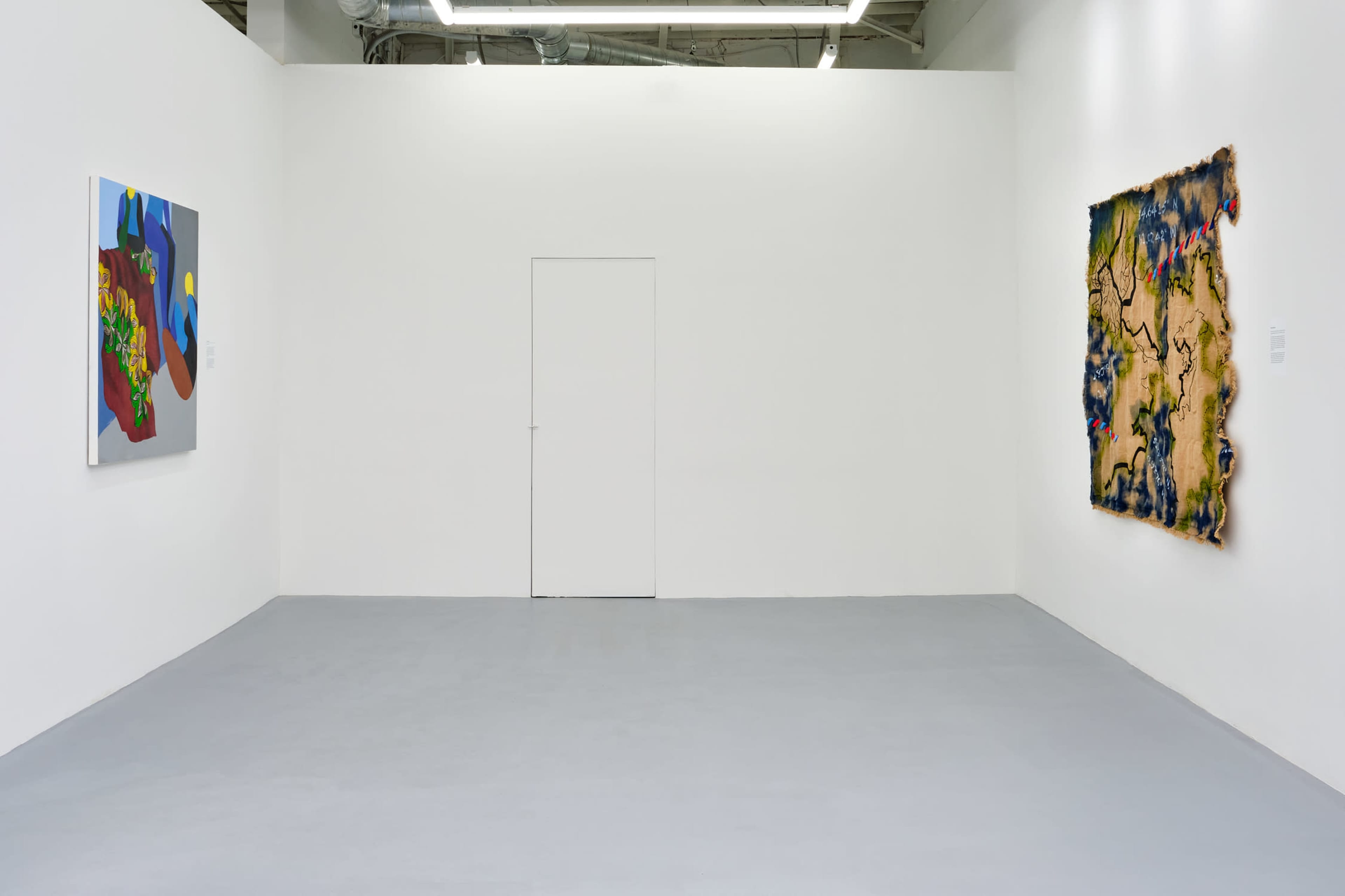 A minimalist art gallery interior with two abstract paintings displayed on white walls and a closed door on the far wall.