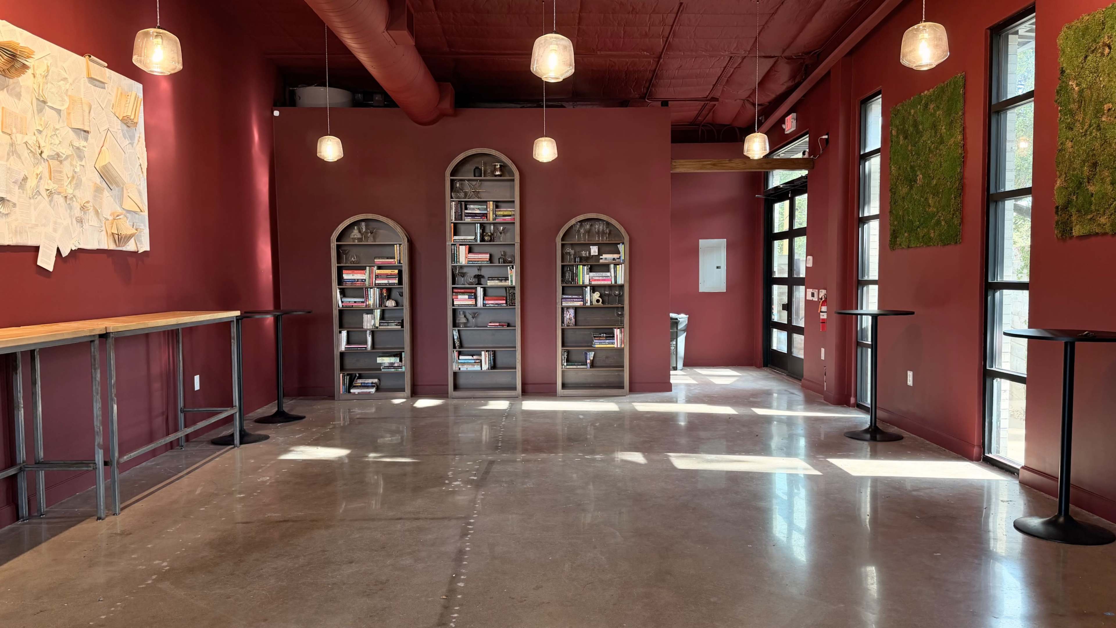 The image shows an interior space with red walls, shelves containing books, and a polished concrete floor.