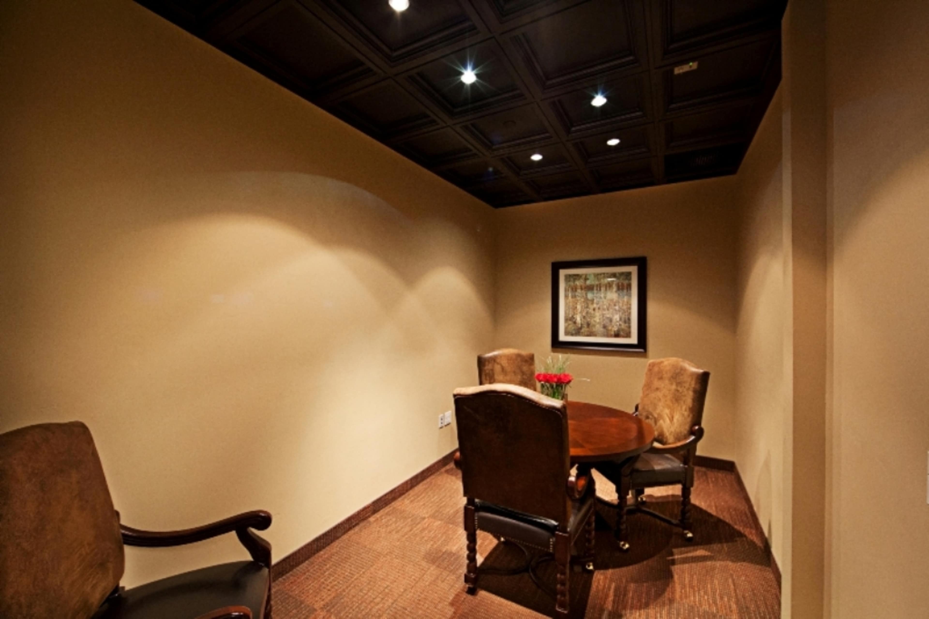 A small meeting room featuring a round table surrounded by four chairs and a framed artwork on the wall.