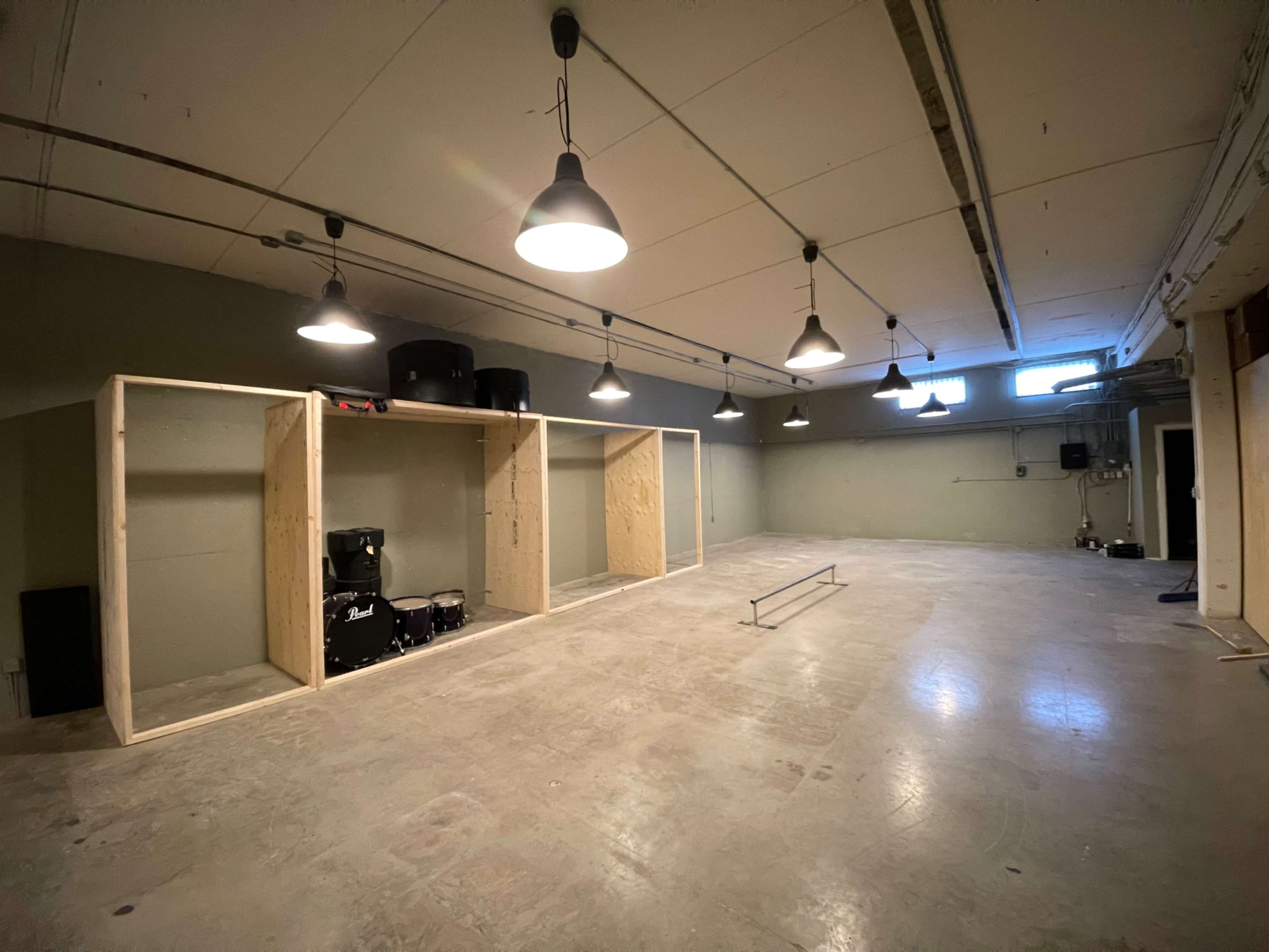 A large, unfinished room with wooden shelving units, several black musical instruments, and overhead lighting.