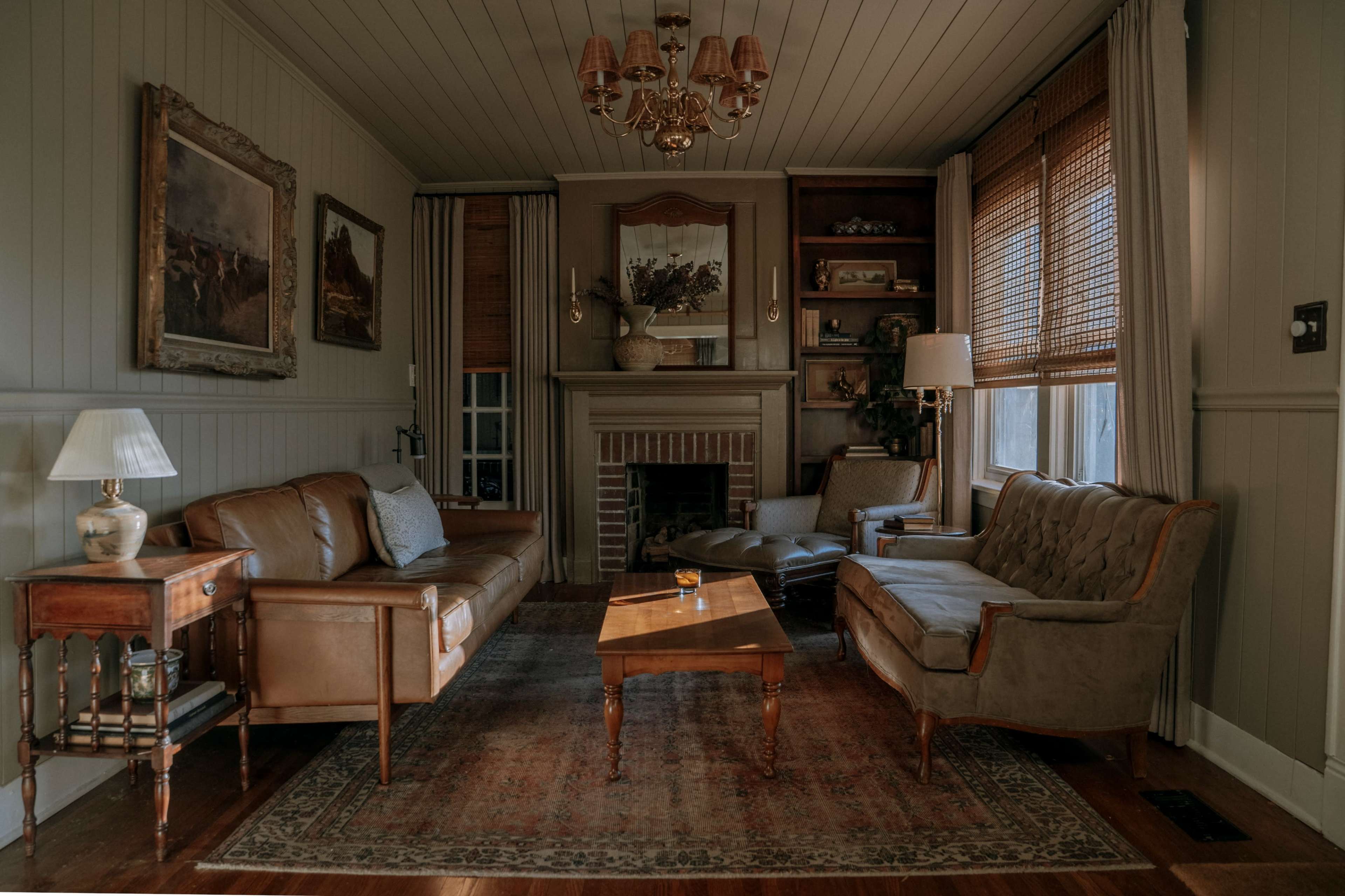 The living room features a combination of leather and upholstered sofas, a wooden coffee table, and a fireplace, all surrounded by warm-toned walls and decorative artwork.