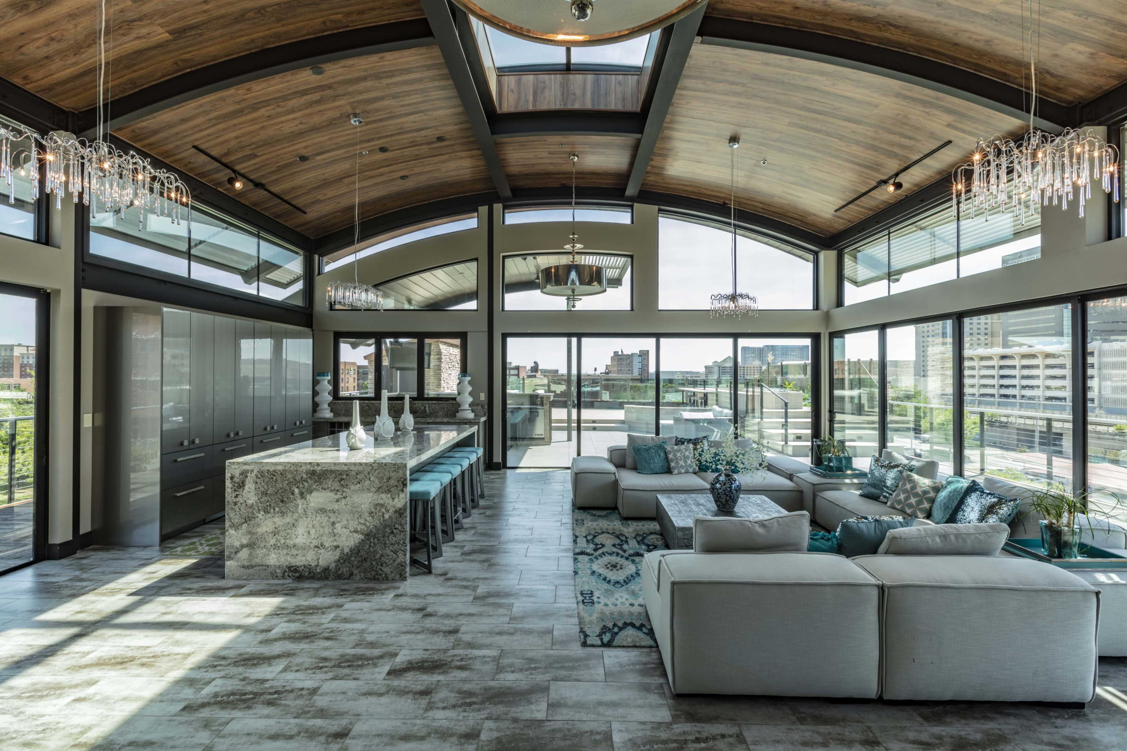A modern interior space with large windows, wooden beams on the ceiling, and a spacious area filled with furniture.