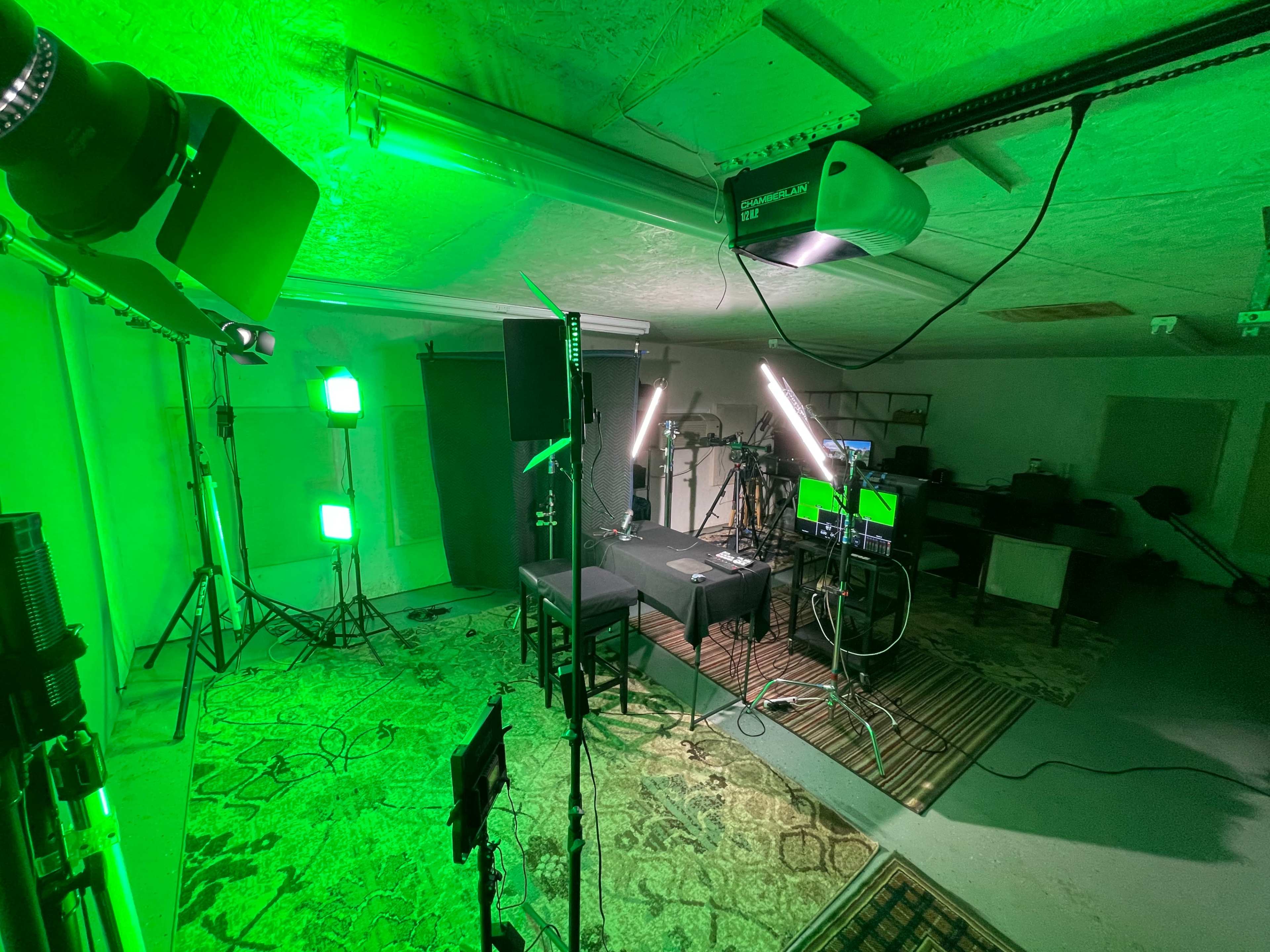A studio setup with green lighting, cameras, and equipment arranged around a central table.