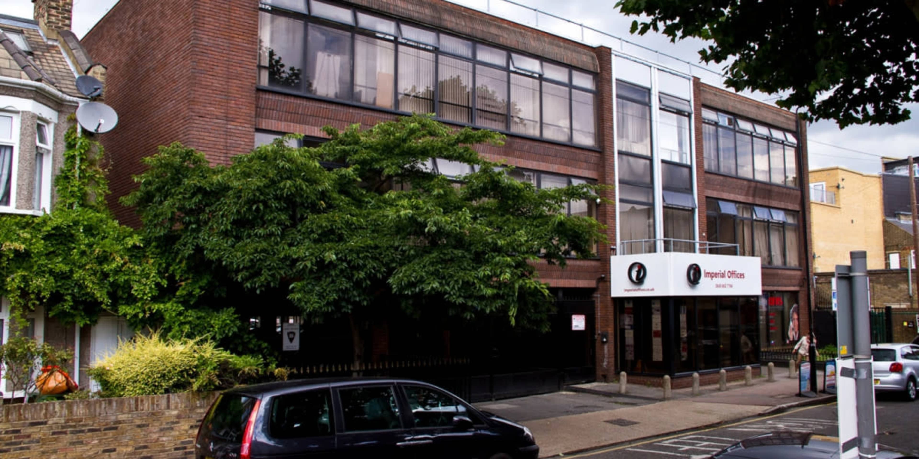 The image shows a three-story brick building with large windows and a sign for "Imperial Offices" in front.