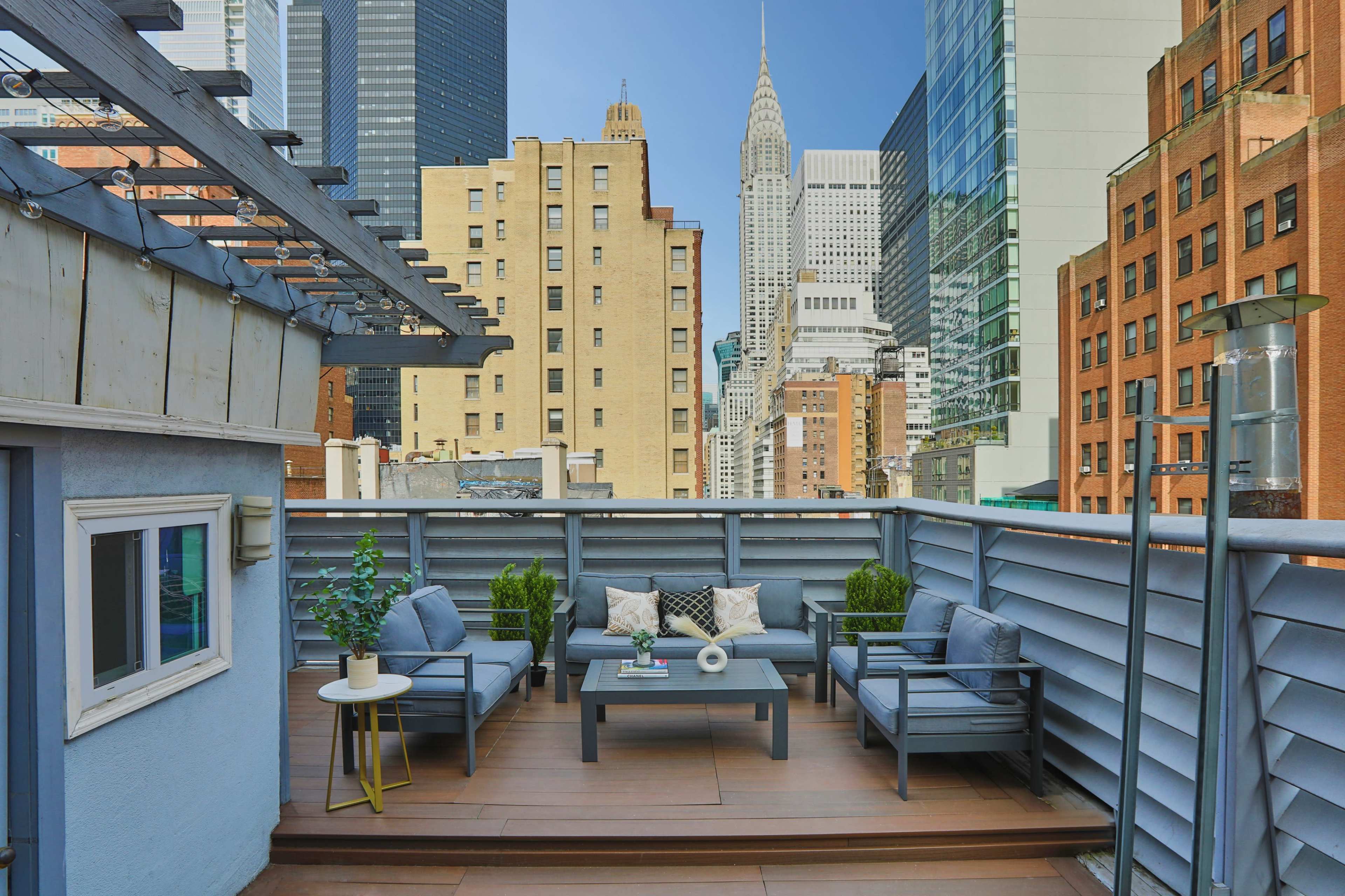 A rooftop terrace features modern seating and a coffee table, with views of skyscrapers, including the Empire State Building, in the background.