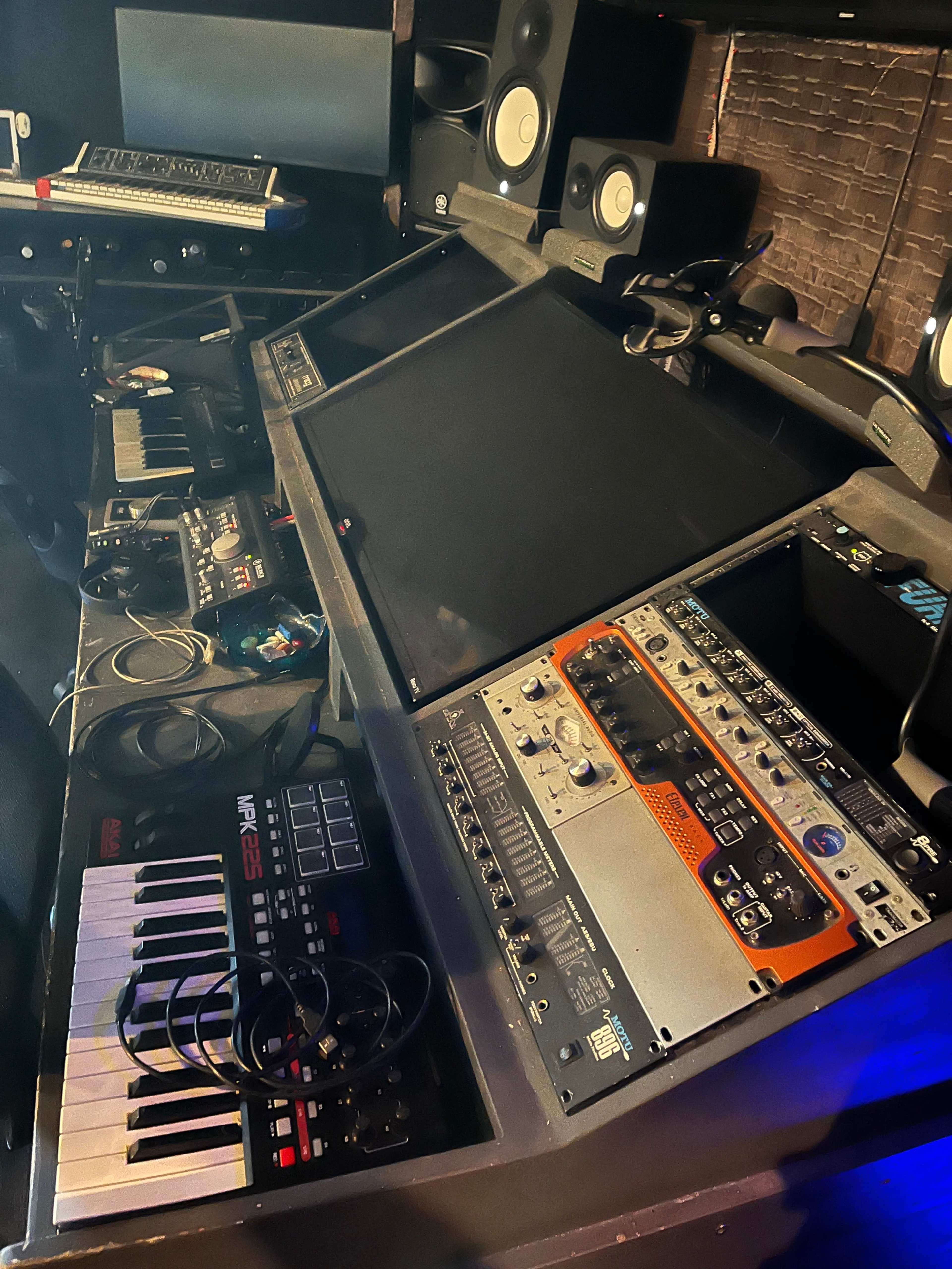 A music production studio with various electronic instruments and audio equipment arranged on a desk.
