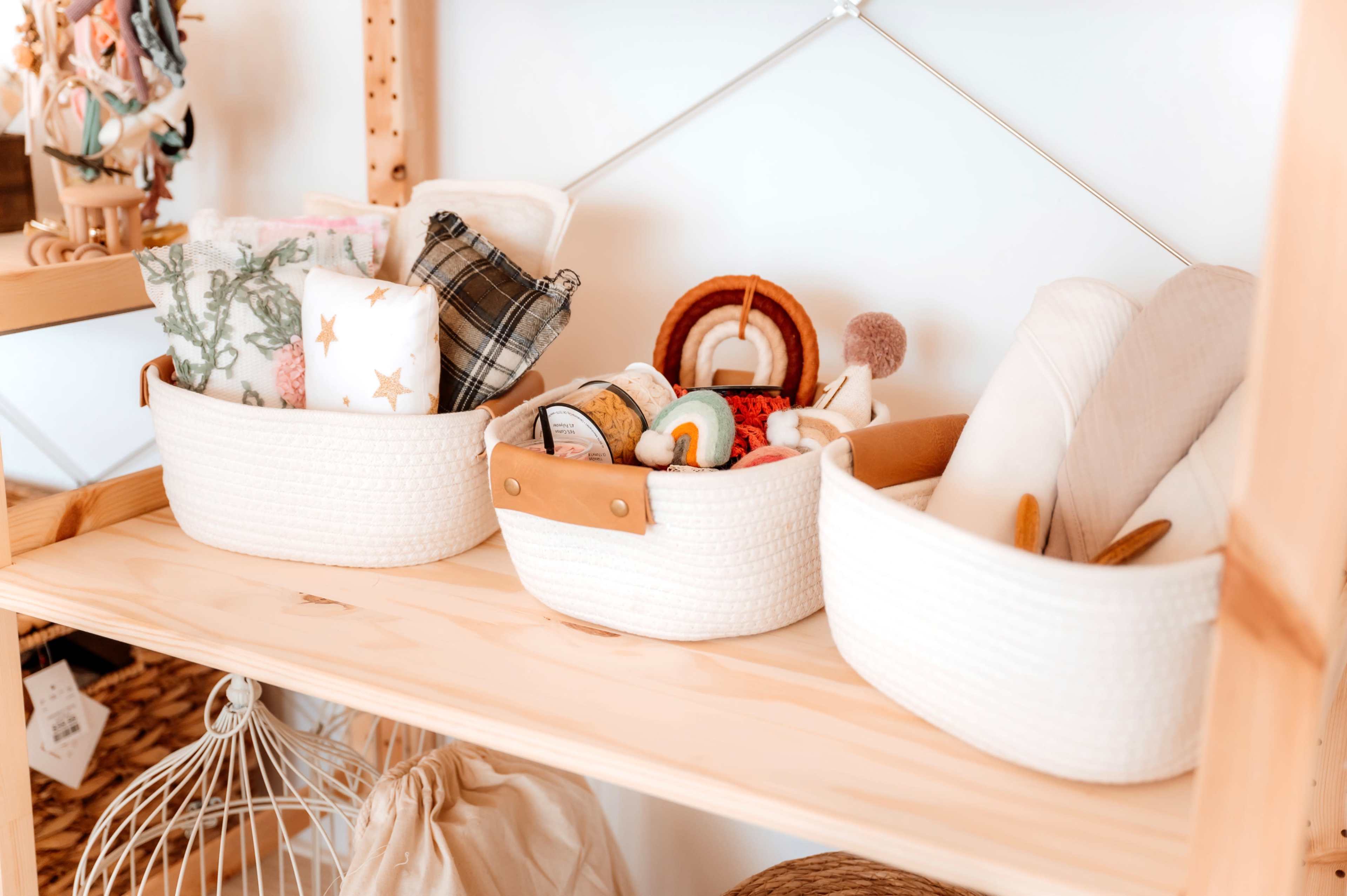 The image shows three woven storage baskets filled with various toys and fabric items on a wooden shelf.