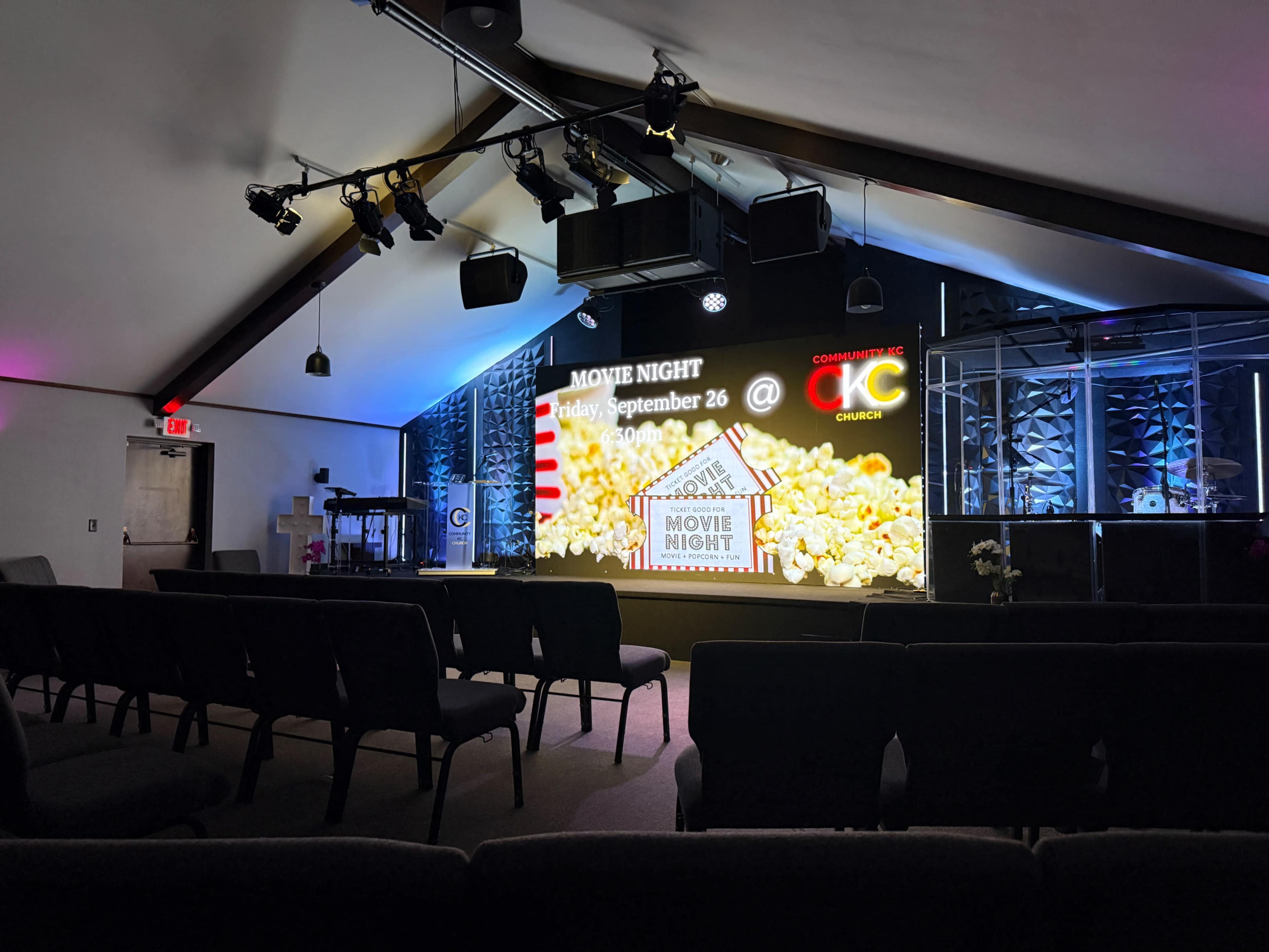 The image shows a church interior set up for a movie night event, featuring a large screen displaying popcorn graphics and event details.
