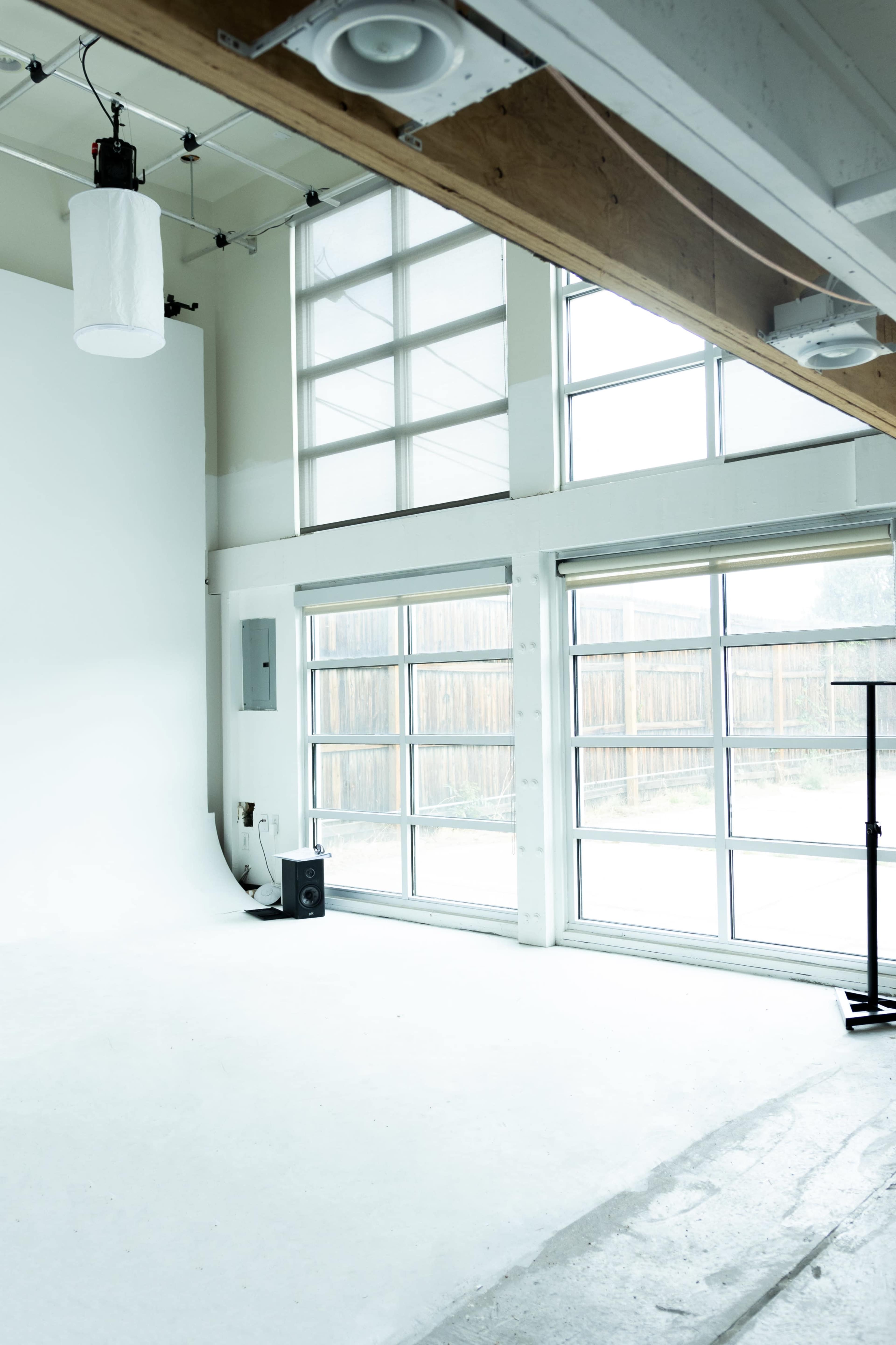 A spacious, well-lit photography studio with large windows and a white backdrop.