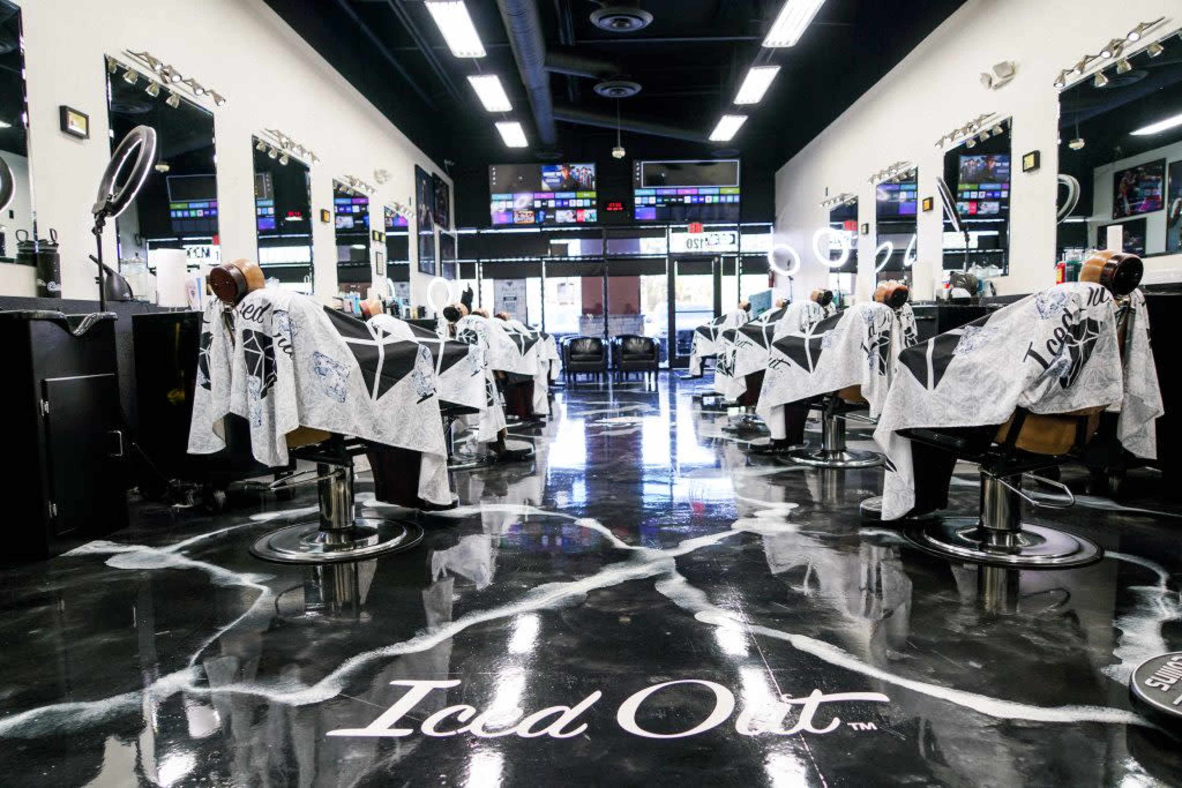 The interior of a modern barbershop features multiple styling stations with chairs, mirrors, and a unique patterned floor.
