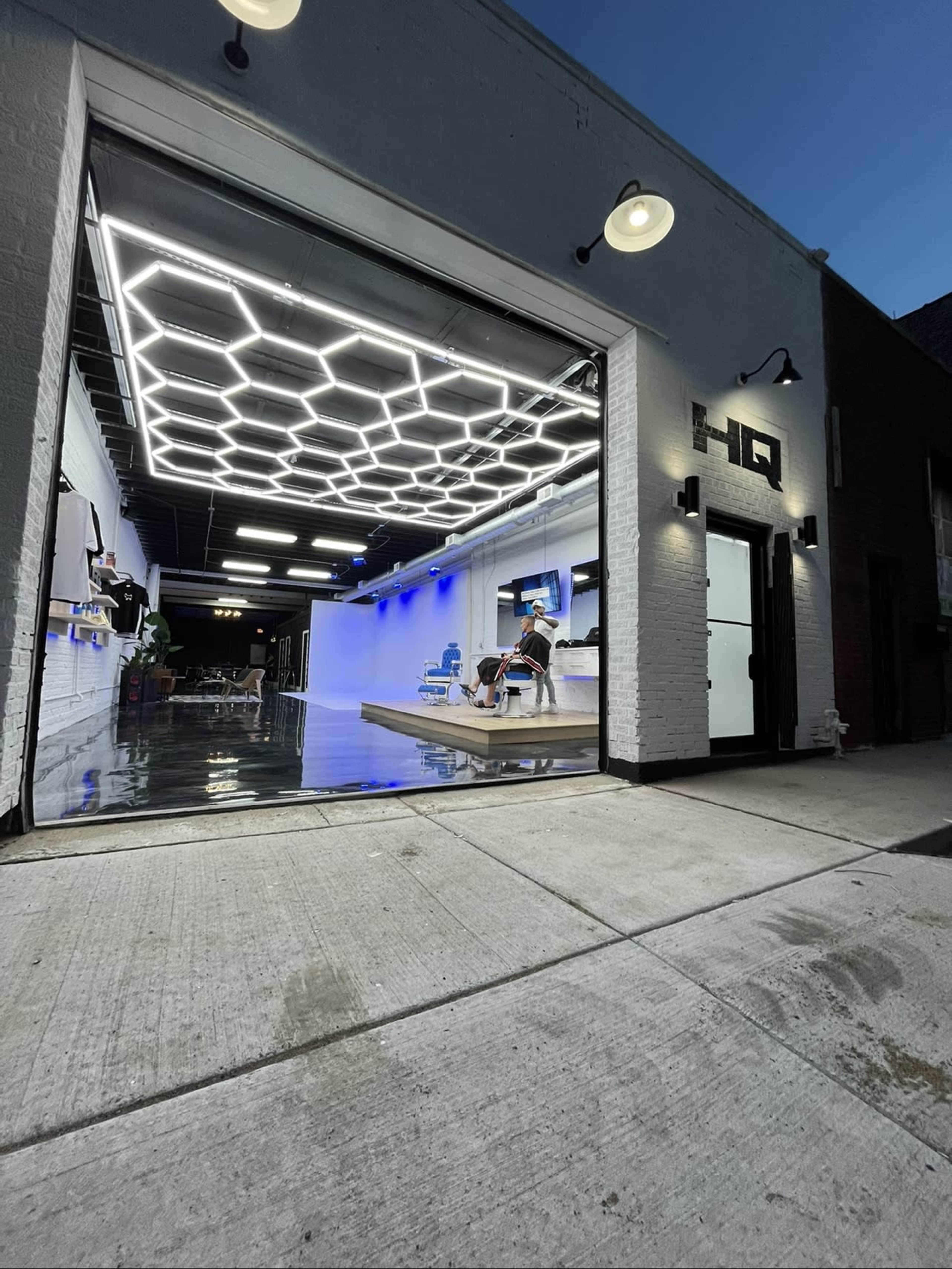 A modern garage space with a hexagonal ceiling light design, partially open door, and a person seated inside.