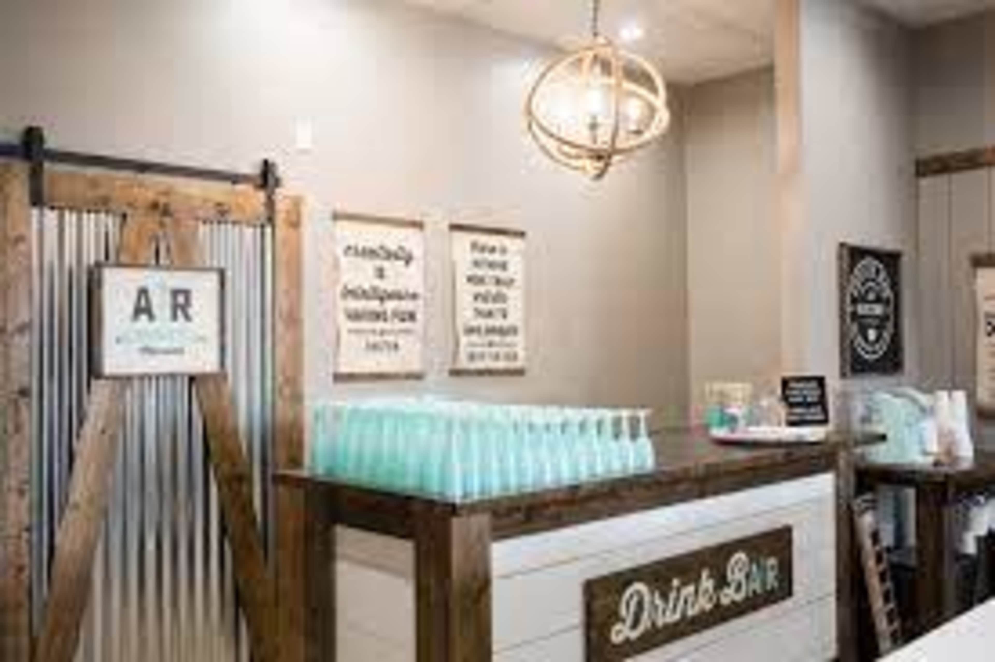 The image shows a drink bar featuring a wooden counter with glass bottles and a variety of signs on the walls.