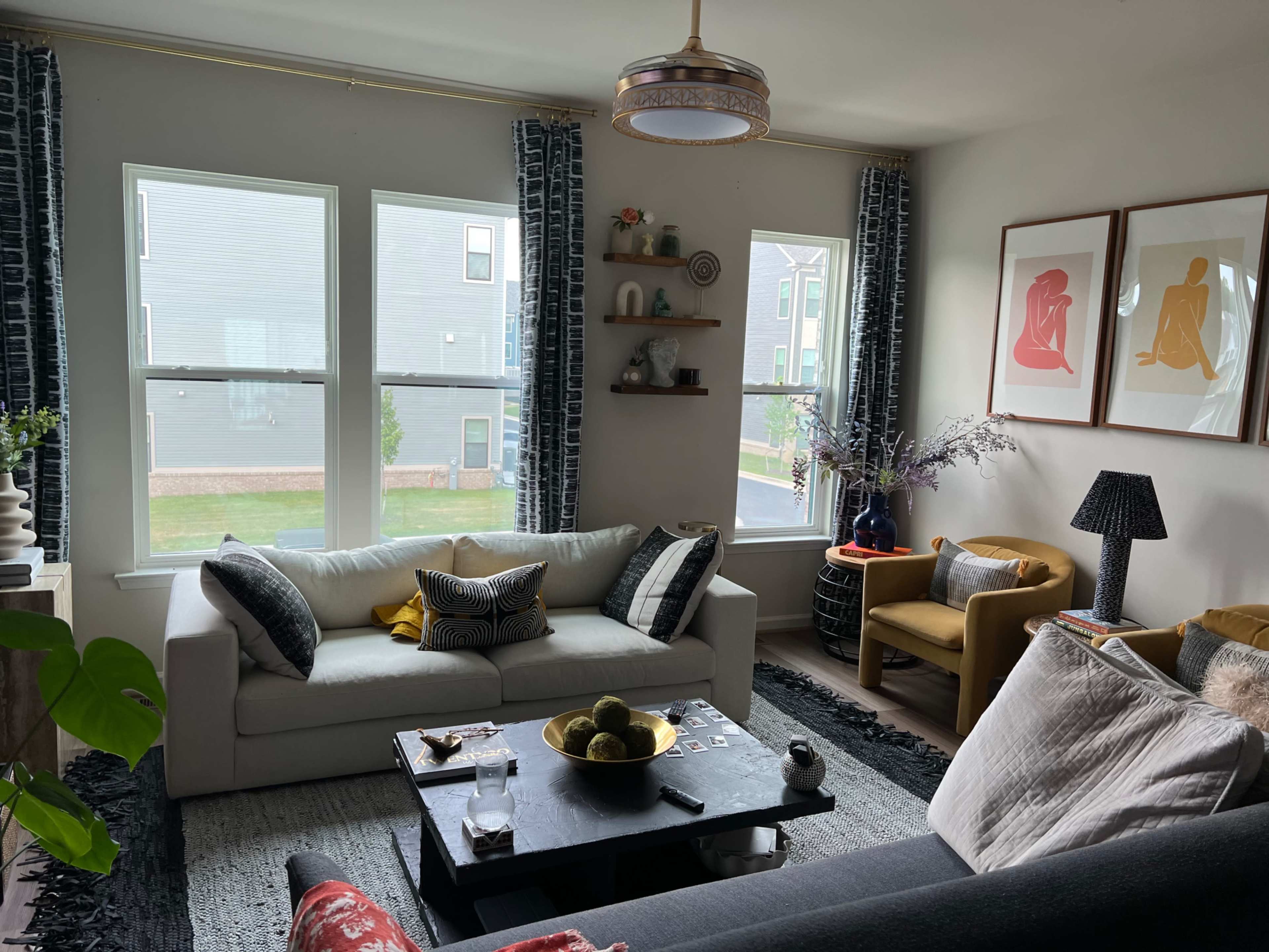 A living room with two sofas, a coffee table in the center, and large windows allowing natural light to enter.