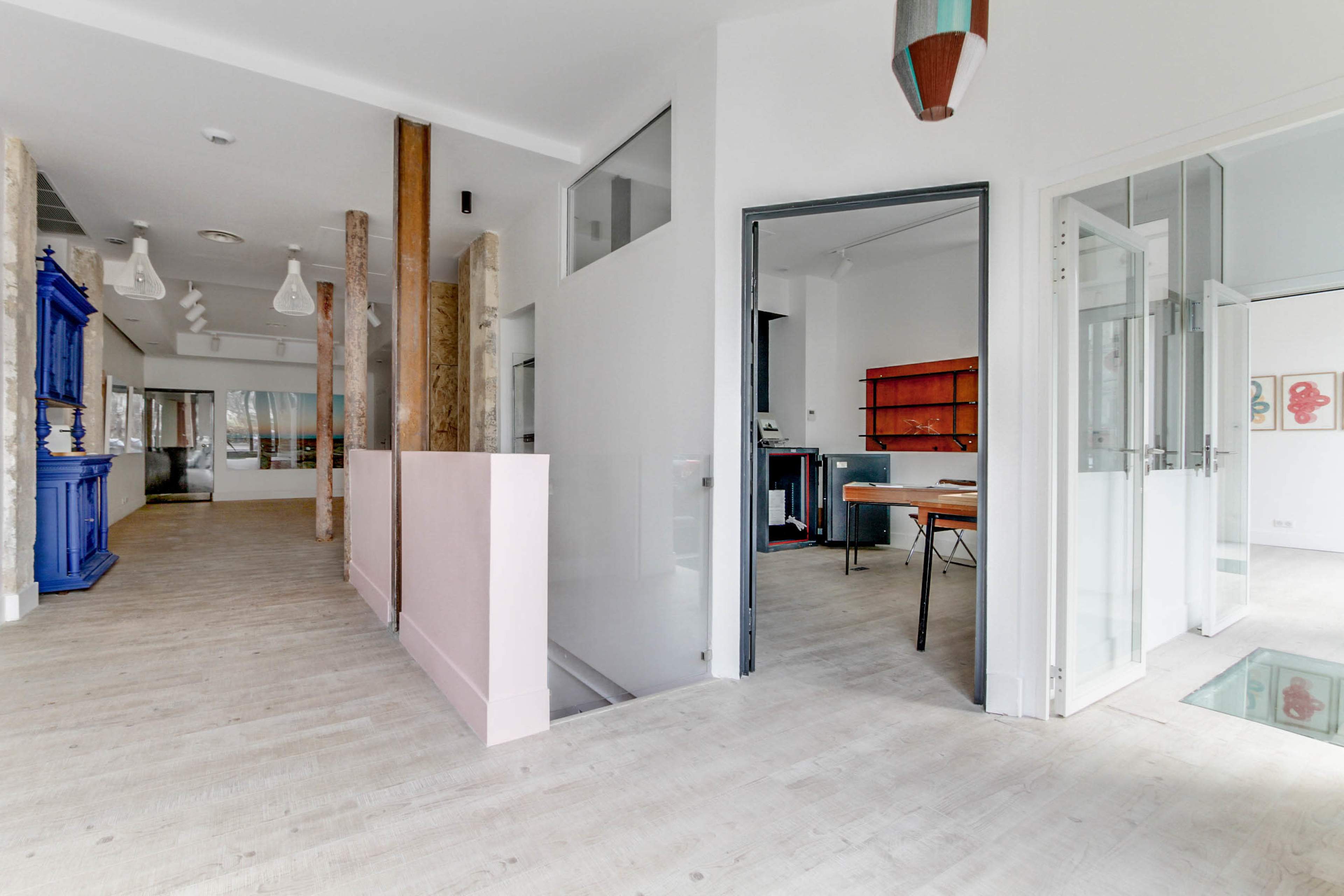 A modern, open hallway leading to a room with a wooden table and a vibrant blue cabinet on the left.