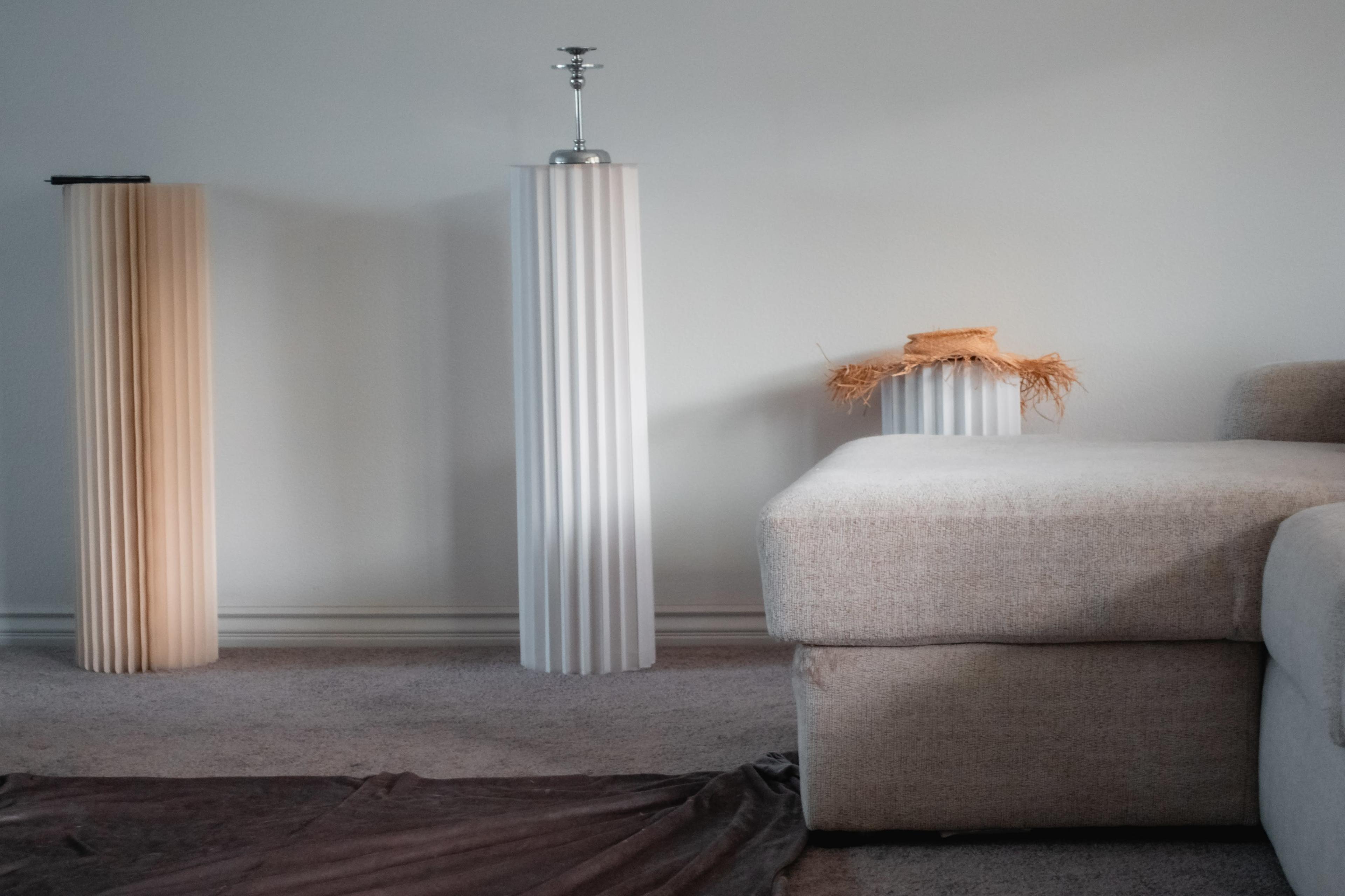 Three vertical decorative light fixtures and a corner of a sofa in a softly lit room.