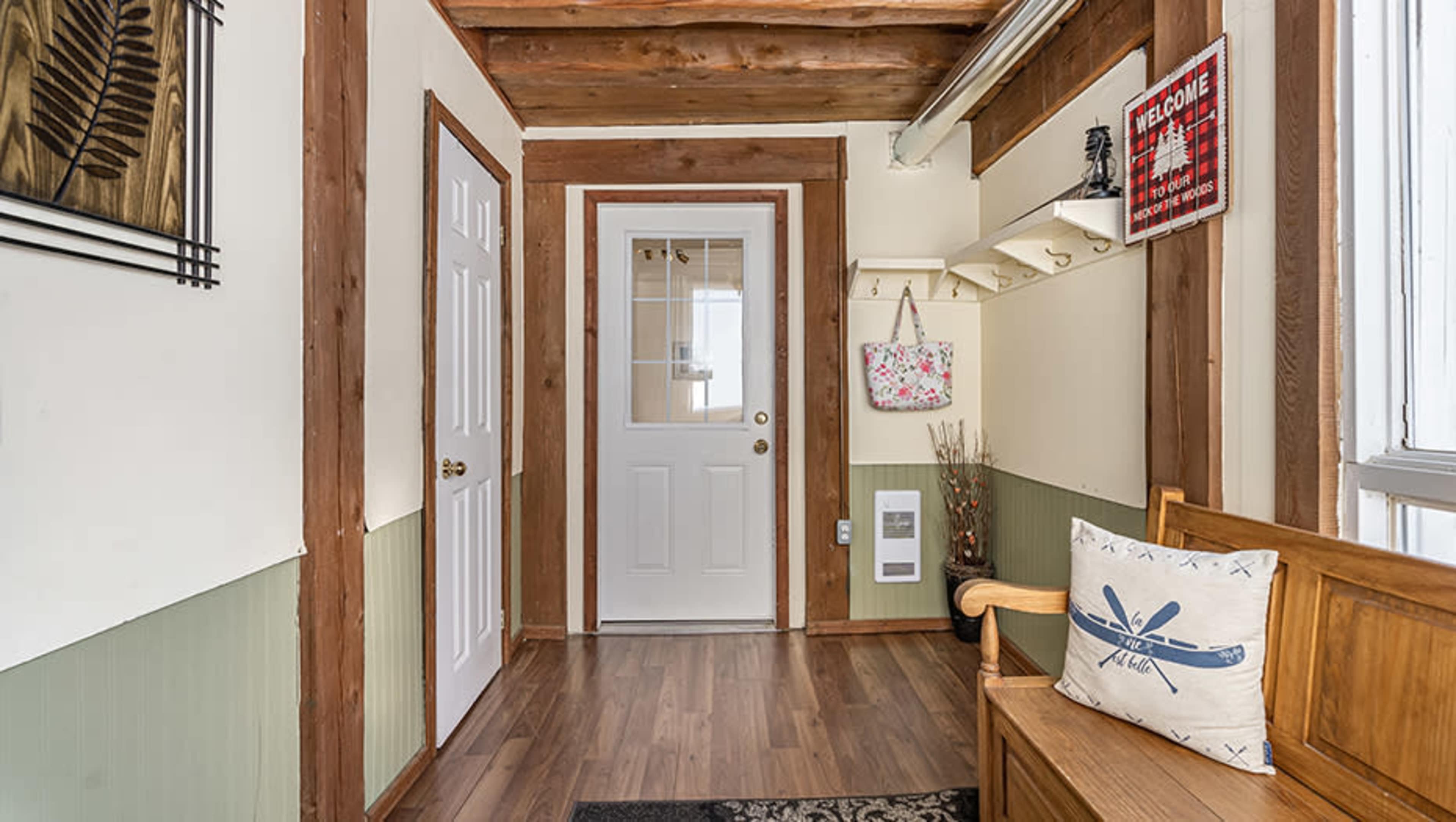 An entryway featuring a wooden bench, a door with a window, and various wall decor elements.
