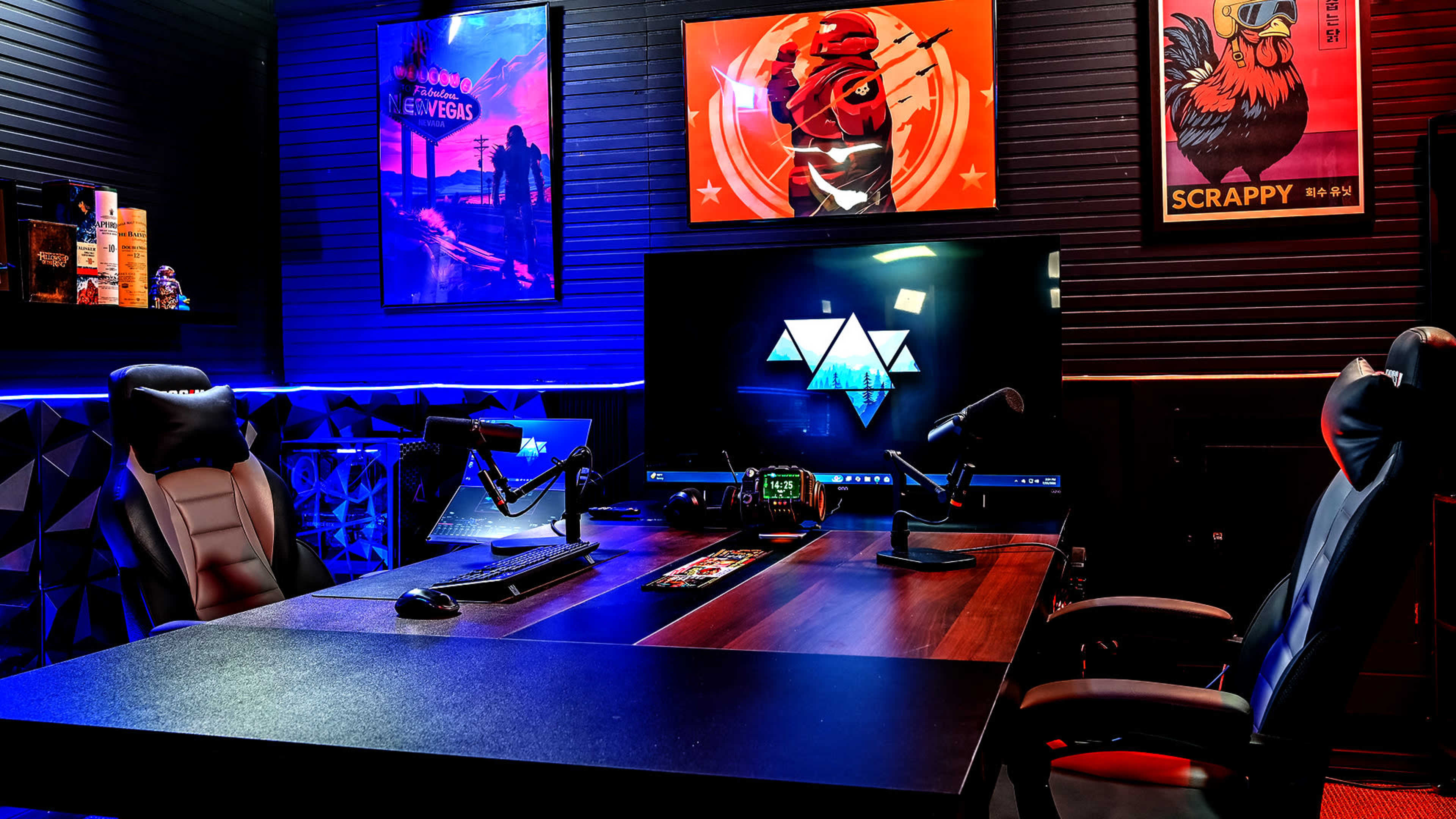 The image shows a modern office space with a large desk, ergonomic chairs, and multiple screens displaying vibrant artwork.