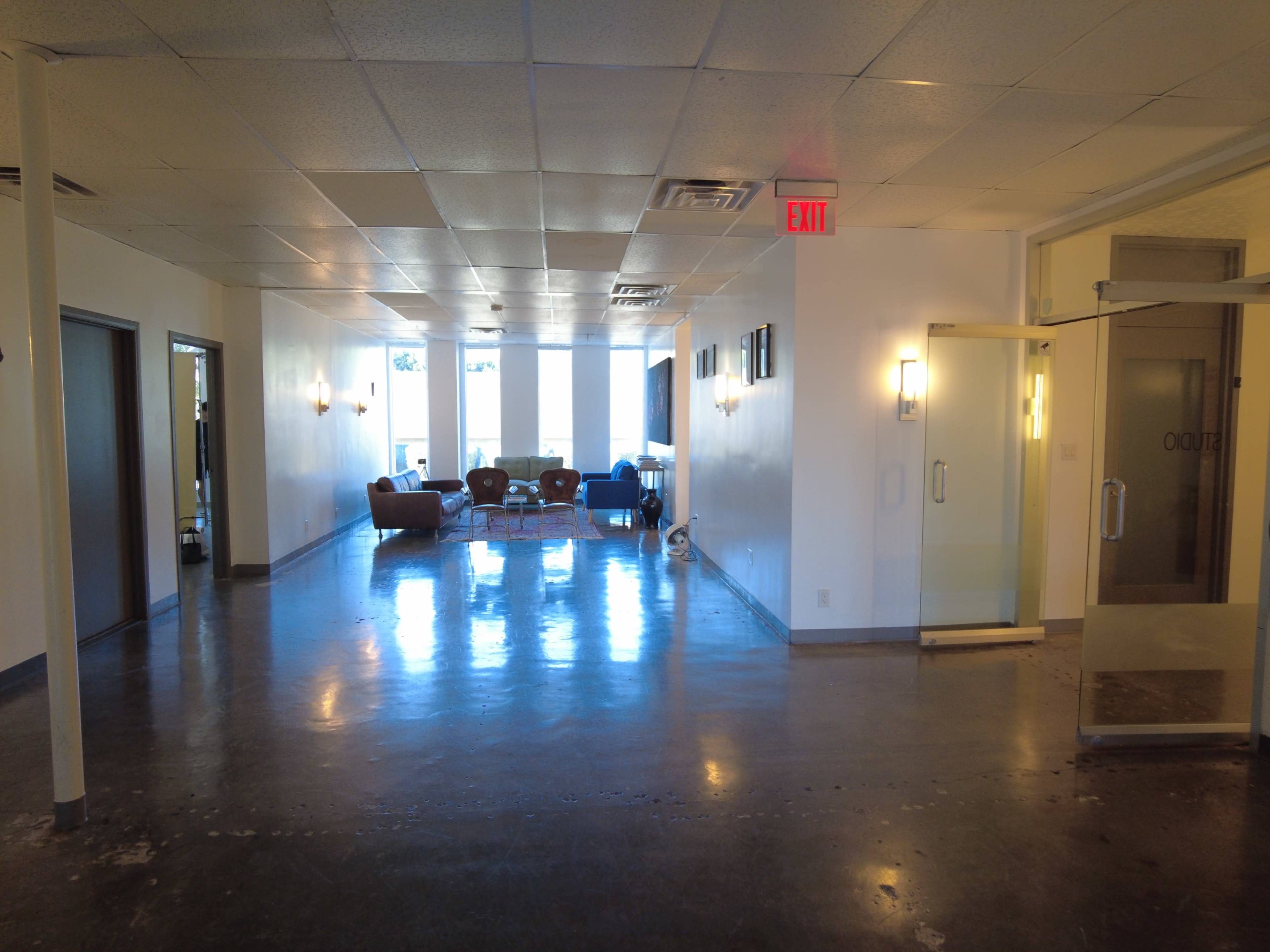 A spacious hallway leads to a well-lit lounge area with modern furniture and large windows.