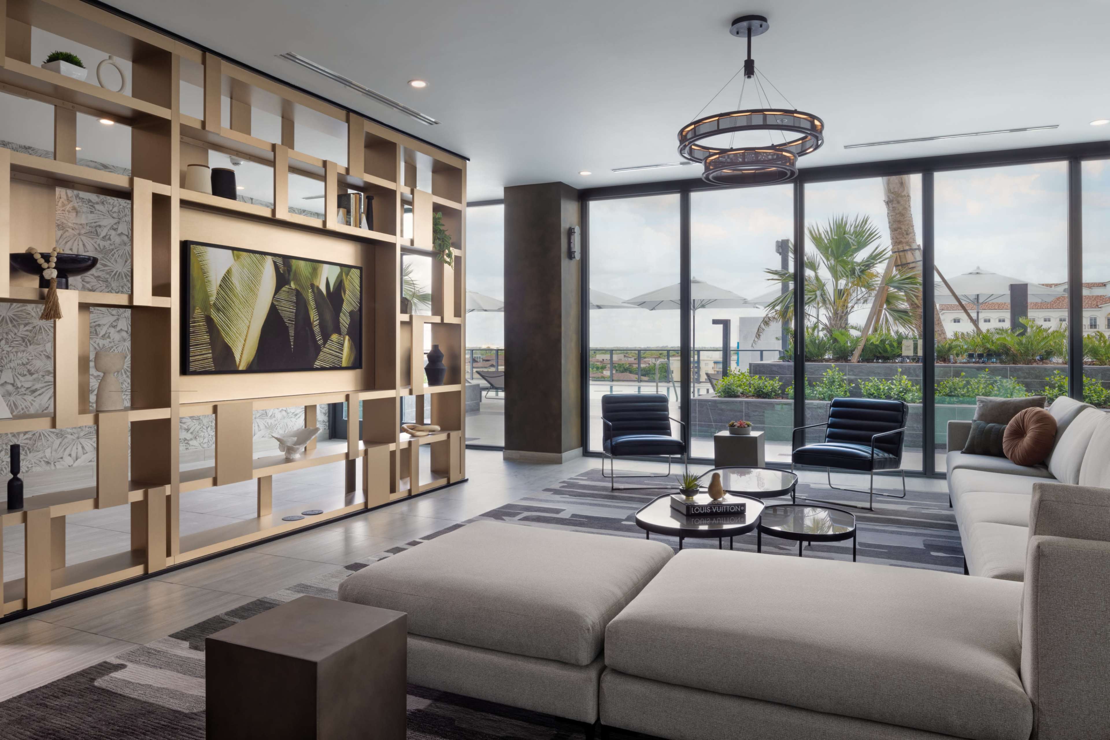 A modern living room features a large sectional sofa, a coffee table, and a wall-mounted television surrounded by decorative shelving.