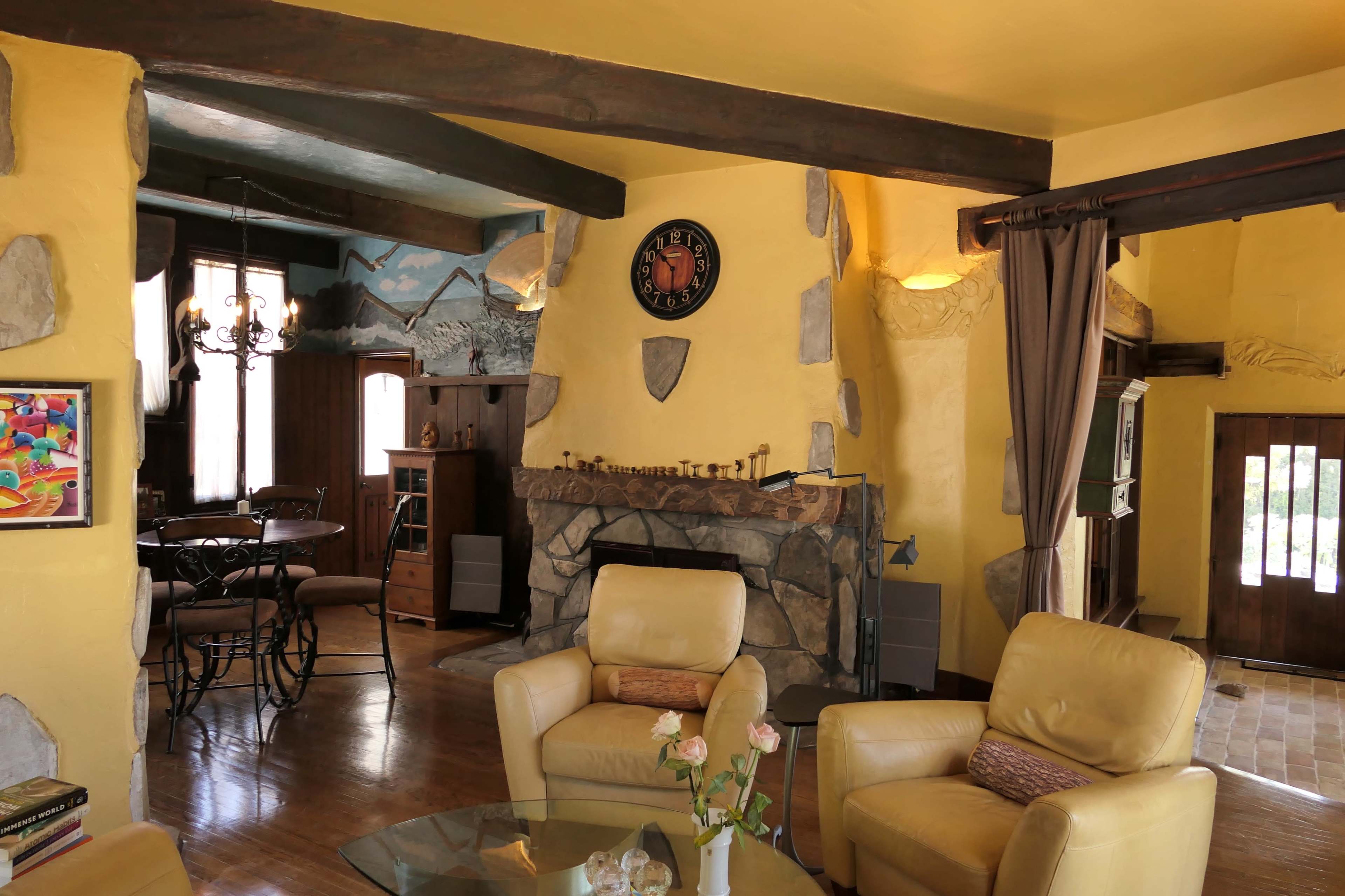 A cozy living room with yellow walls, a stone fireplace, and comfortable seating.