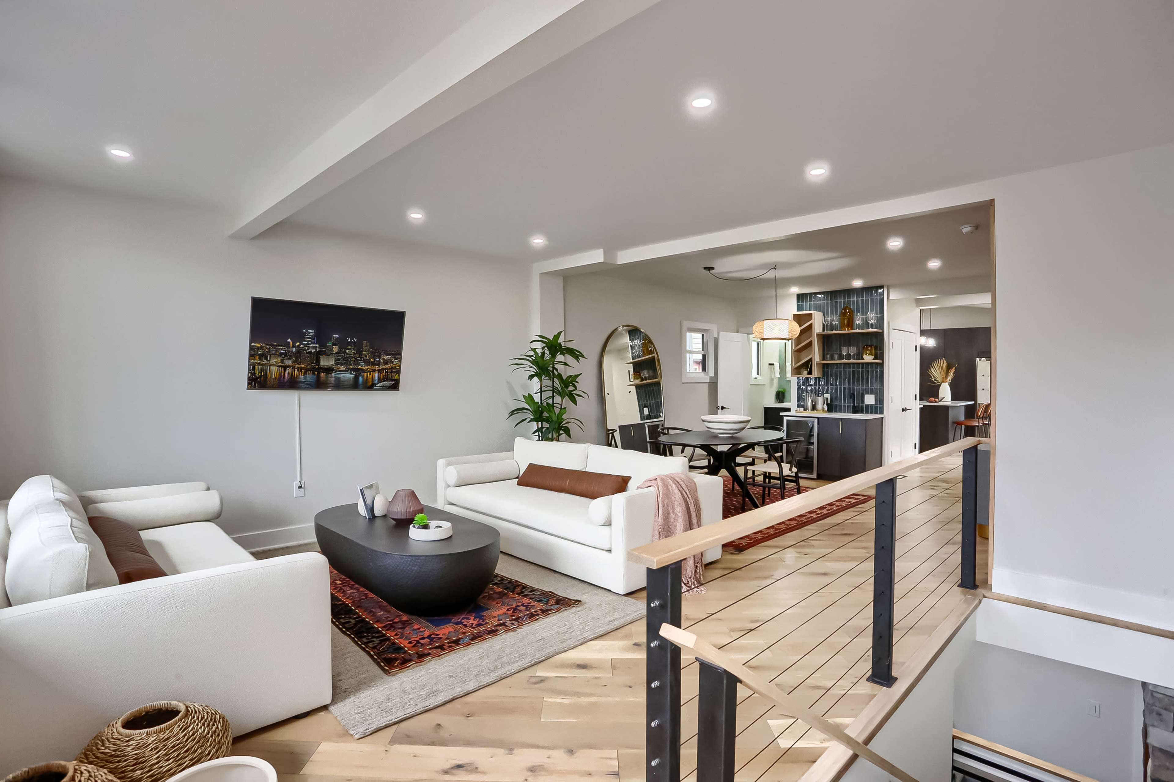 A bright living space features a mix of seating arrangements, a round coffee table in the center, and an open floor plan leading to a dining area.