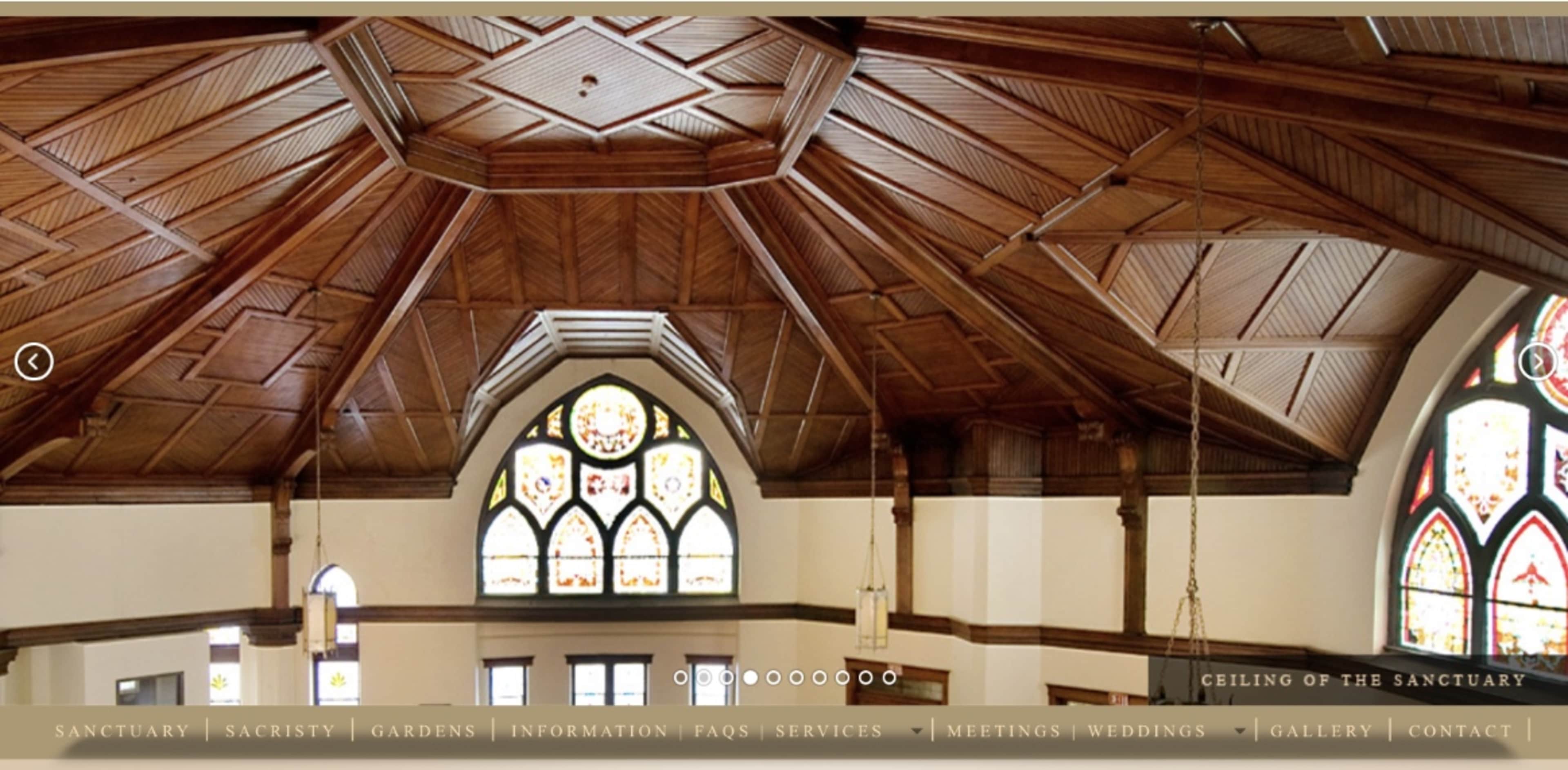 A vaulted wooden ceiling with intricate designs and stained glass windows in a sanctum.