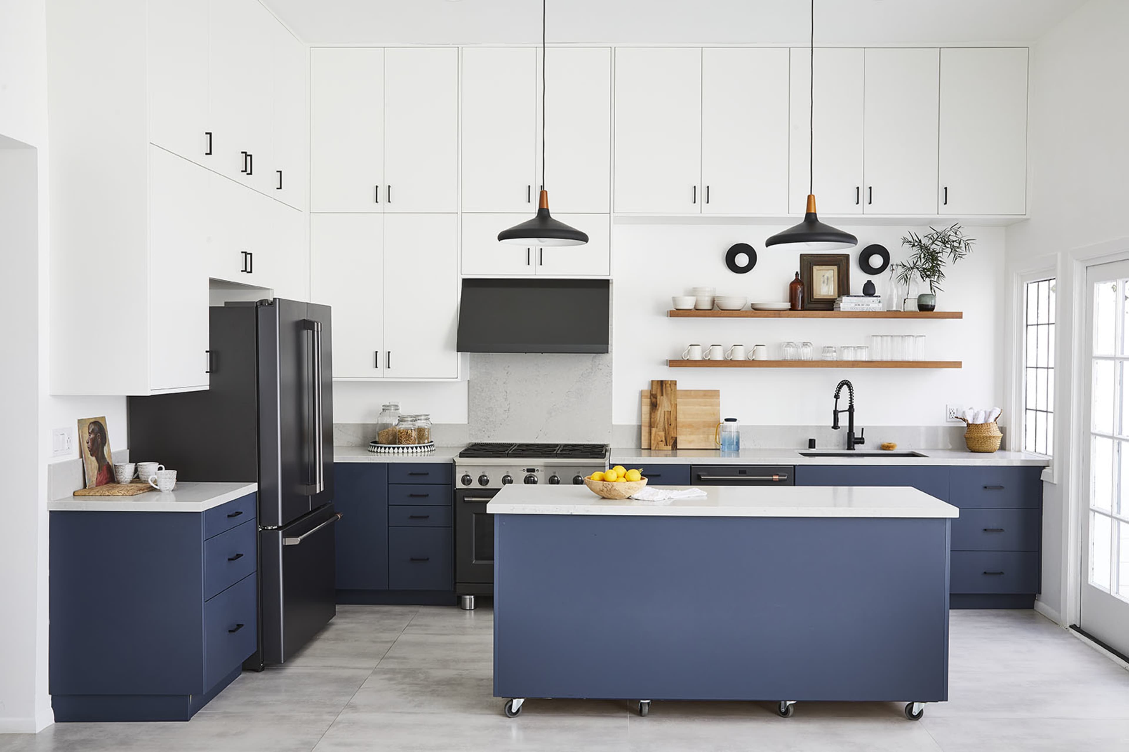 A modern kitchen with navy blue cabinets, a central island, and sleek black appliances against a light-colored backdrop.