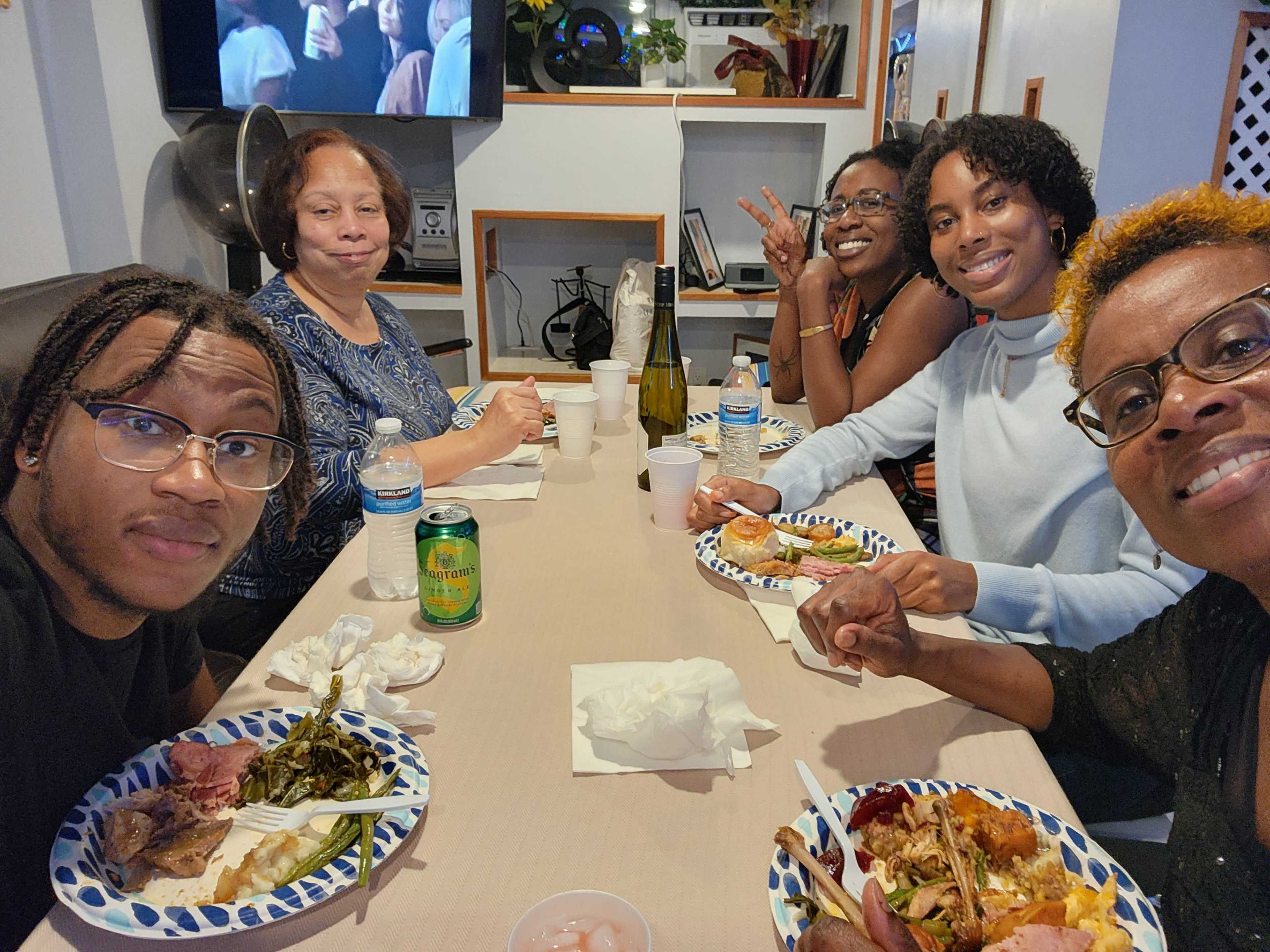 A group of five people sits at a table, enjoying a meal together.