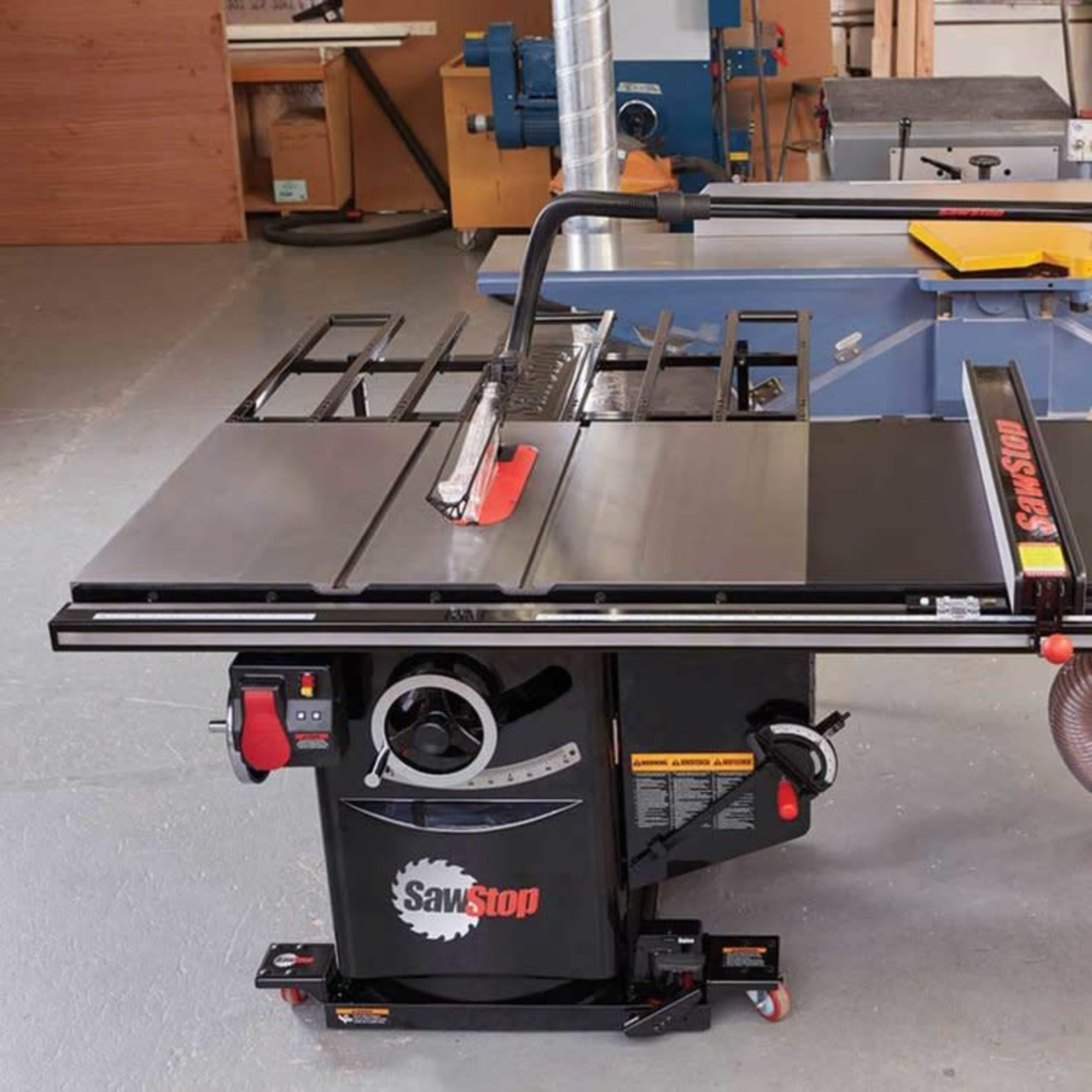 A SawStop table saw with a black surface and a red safety guard set in a workshop environment.