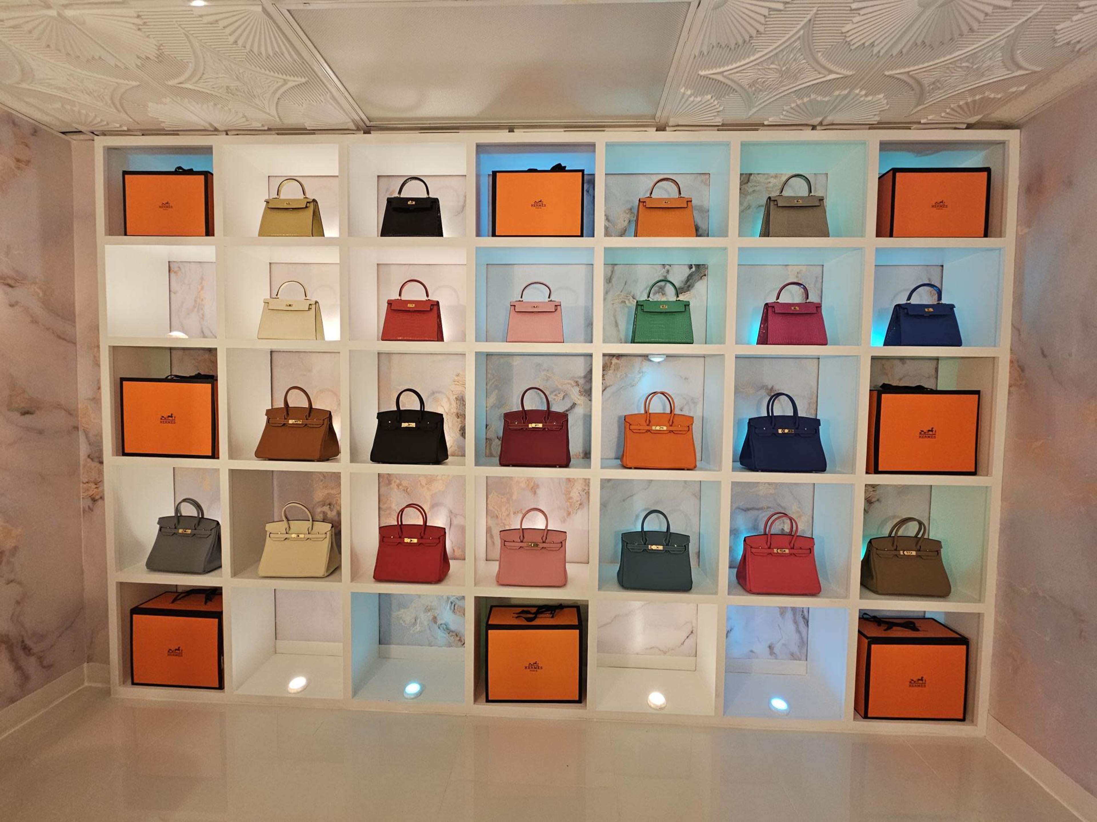 A display wall featuring an array of handbags on shelves, arranged in a grid with a mix of colors and styles.