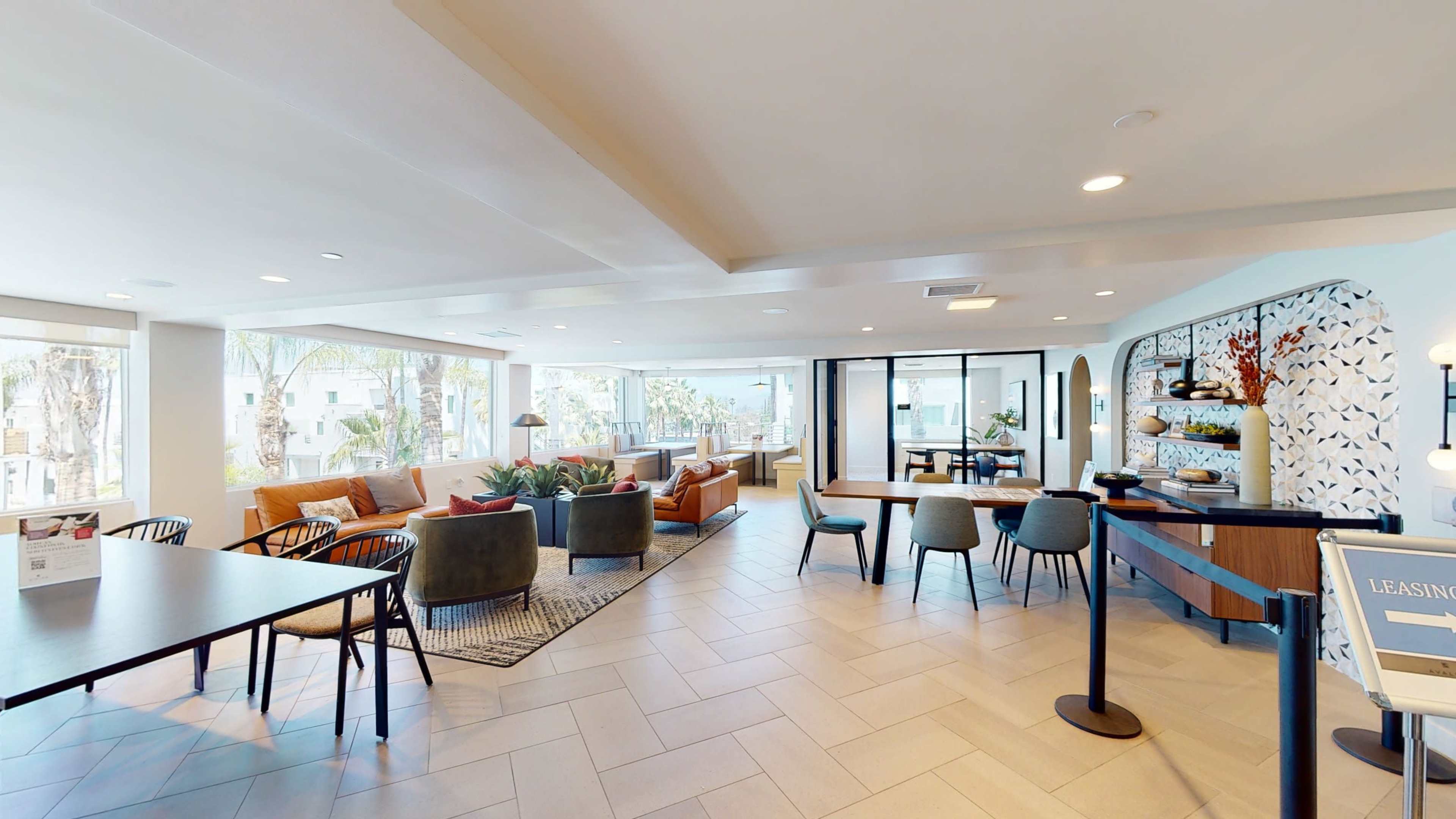 A modern lounge area featuring comfortable seating arrangements and natural light from large windows.