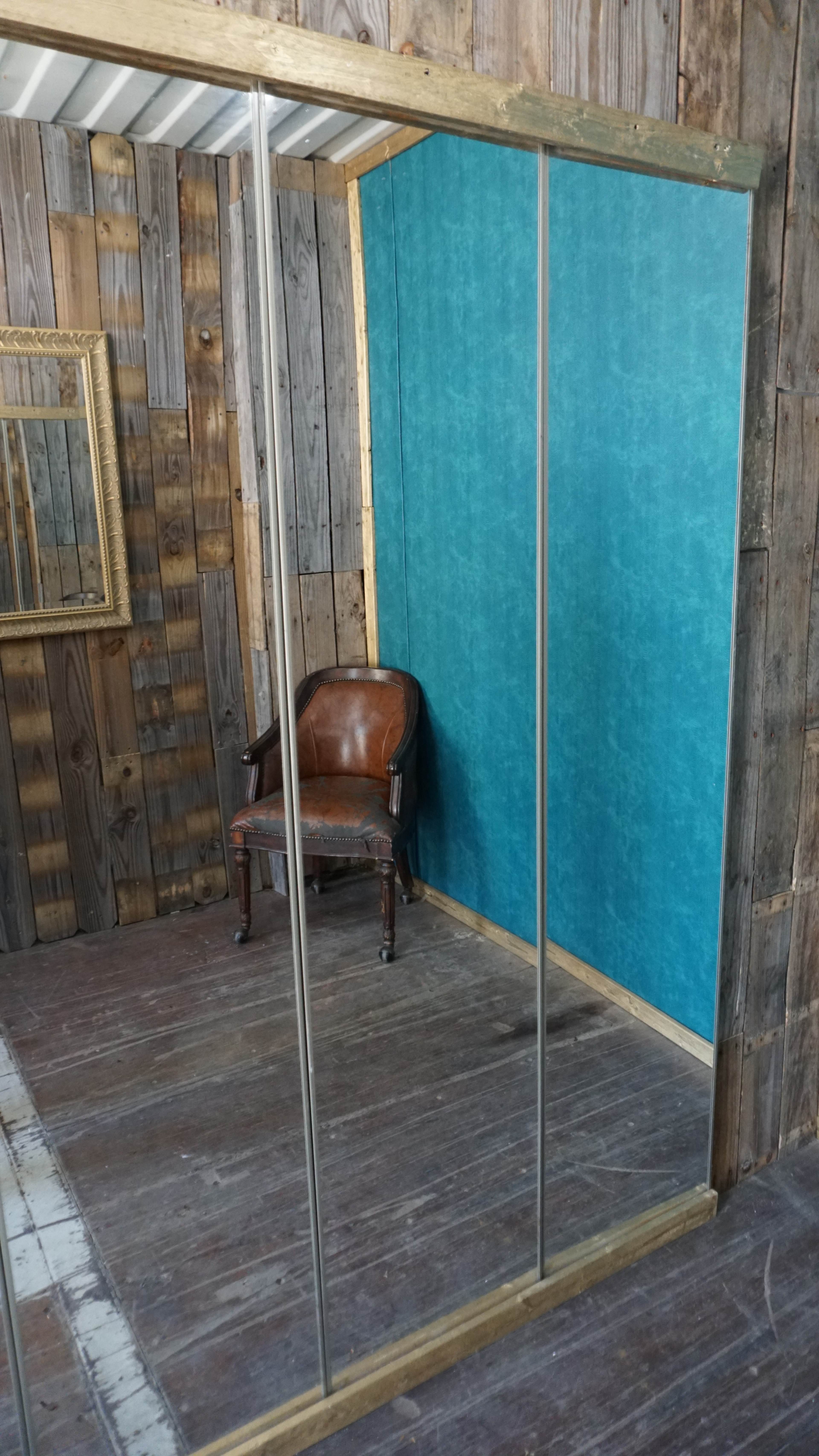 The image shows a room with wooden walls, a turquoise feature wall, and a vintage brown armchair positioned near a mirrored closet.