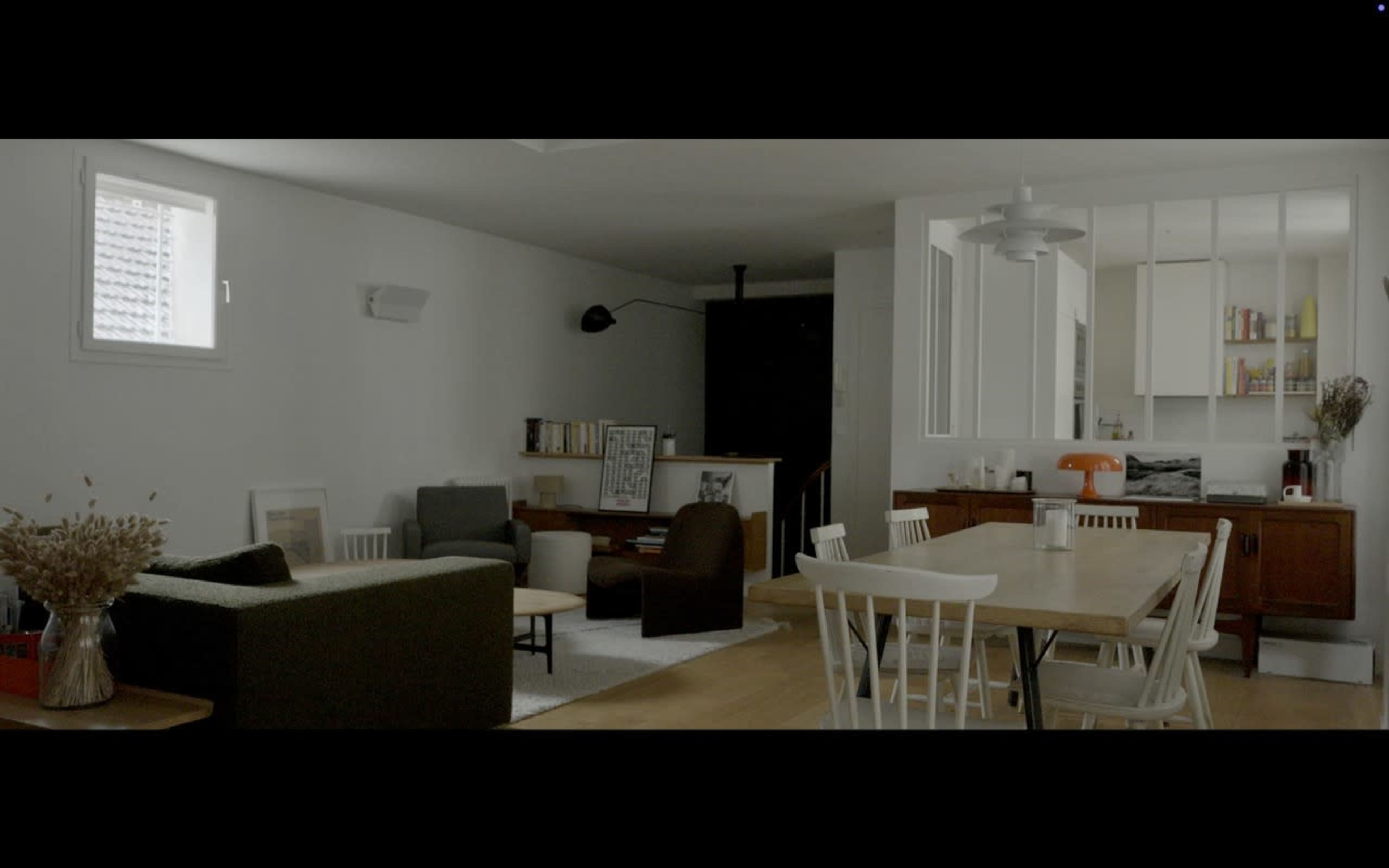 The image shows a modern, minimalist living space featuring a combination of seating areas, a dining table, and open kitchen cabinetry.