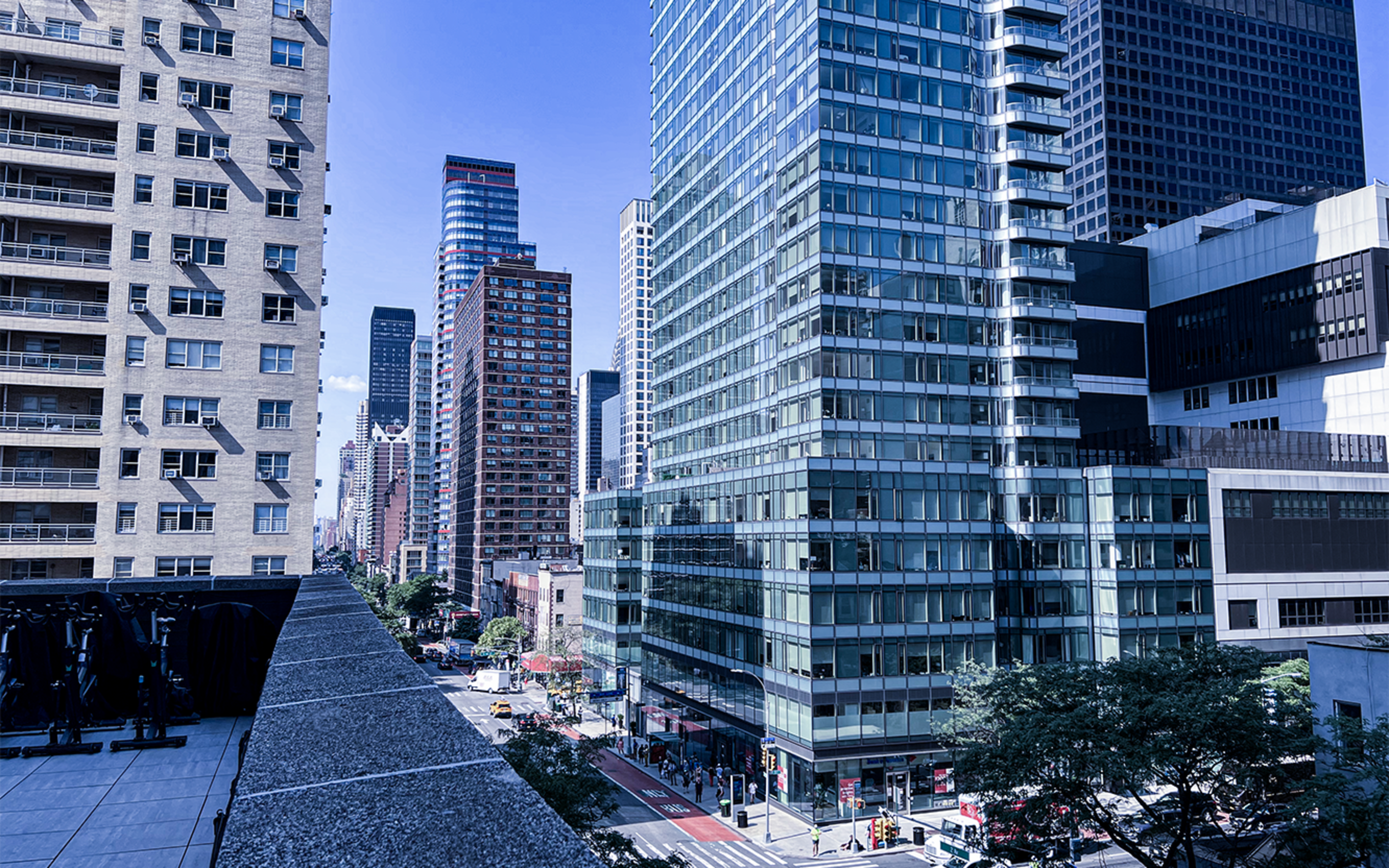 A view of a city skyline featuring tall glass buildings and a clear blue sky.