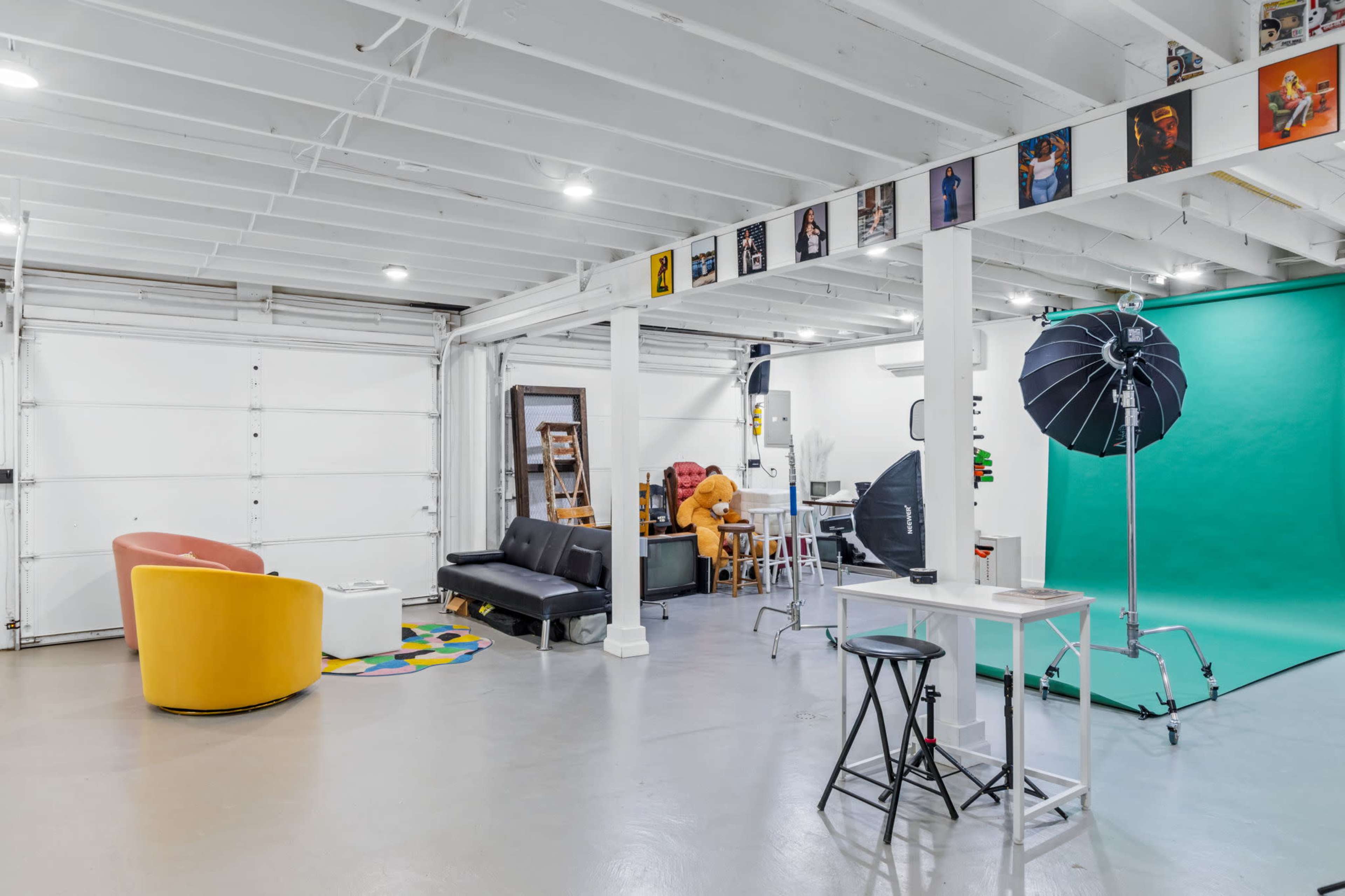 The image shows a spacious studio with various seating areas, a green backdrop, and photography equipment arranged throughout the space.