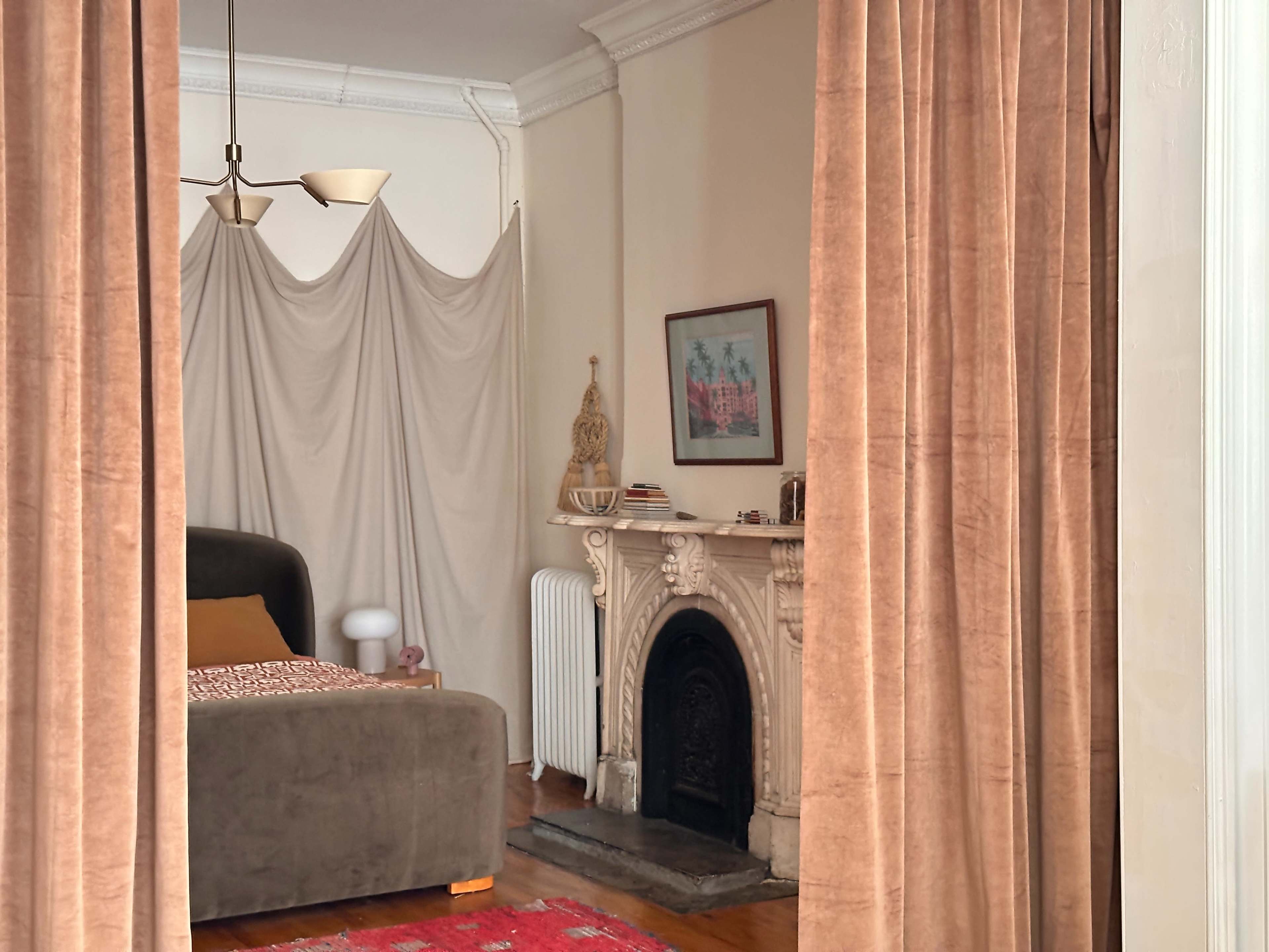 A living room features a brown sofa, a decorative fireplace, and curtains draped at the entrance.