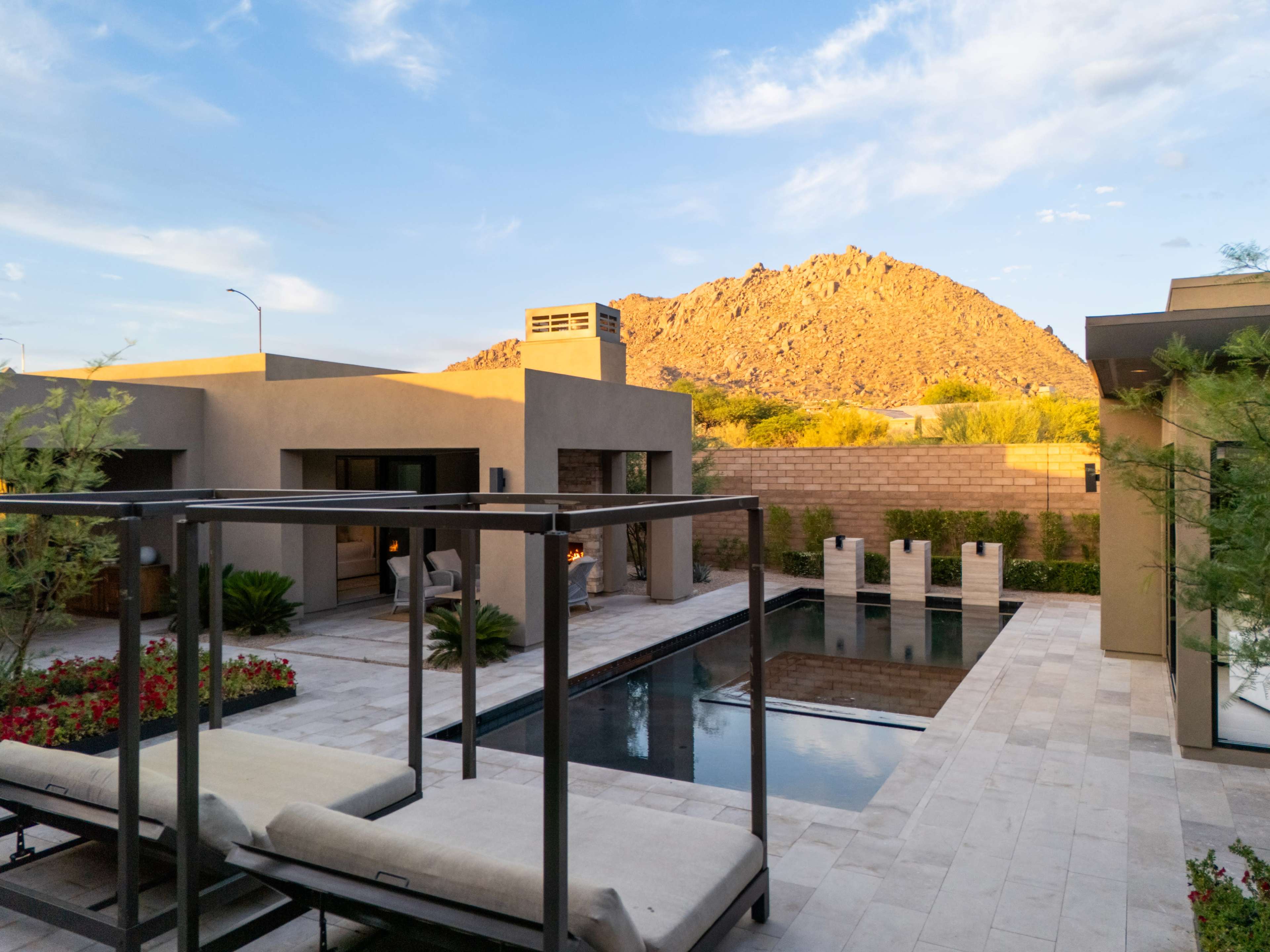 A modern home with a landscaped backyard features a swimming pool and a mountain in the background.