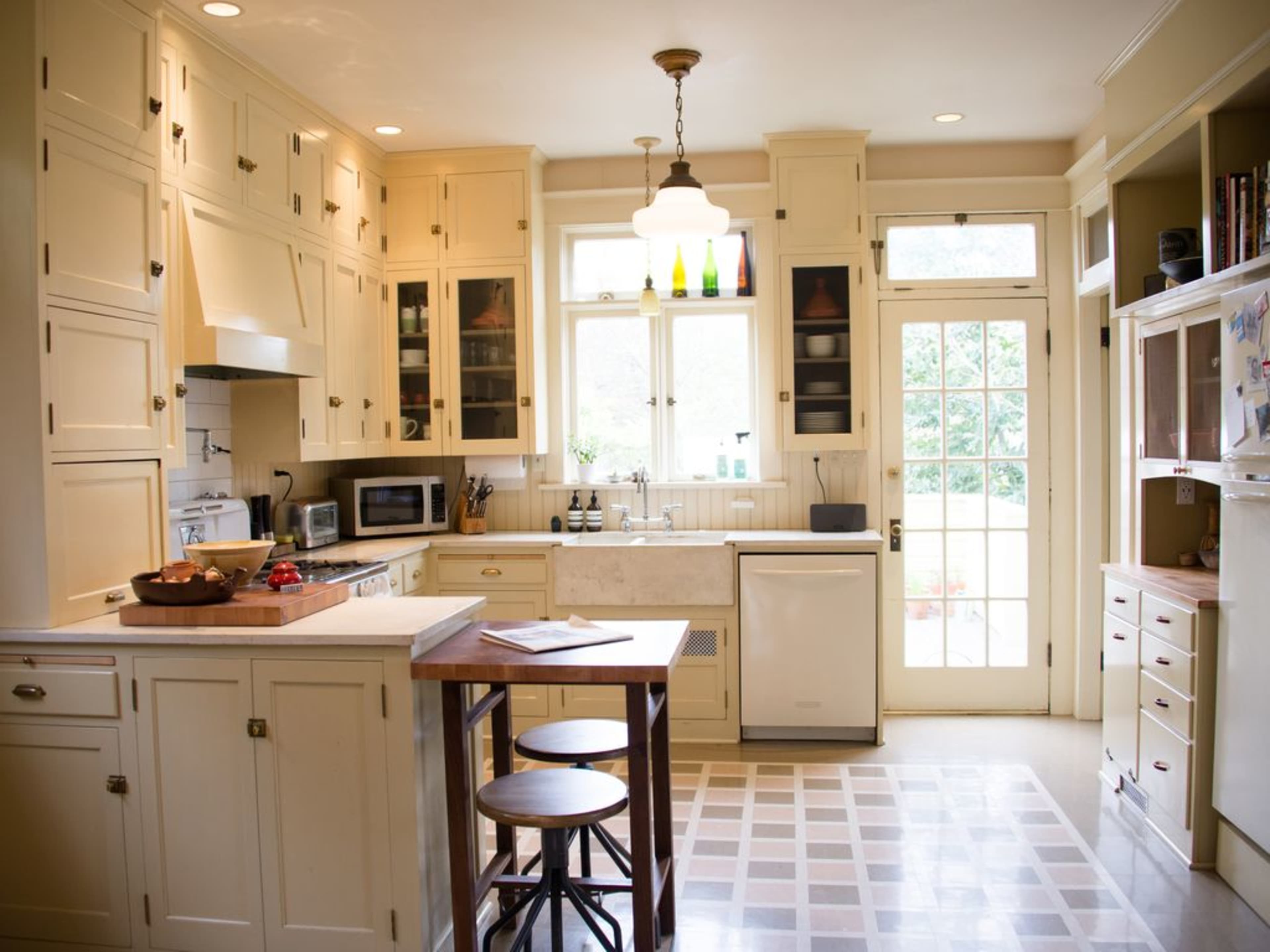 A well-organized kitchen features light-colored cabinetry, a central island with seating, and large windows allowing natural light to illuminate the space.