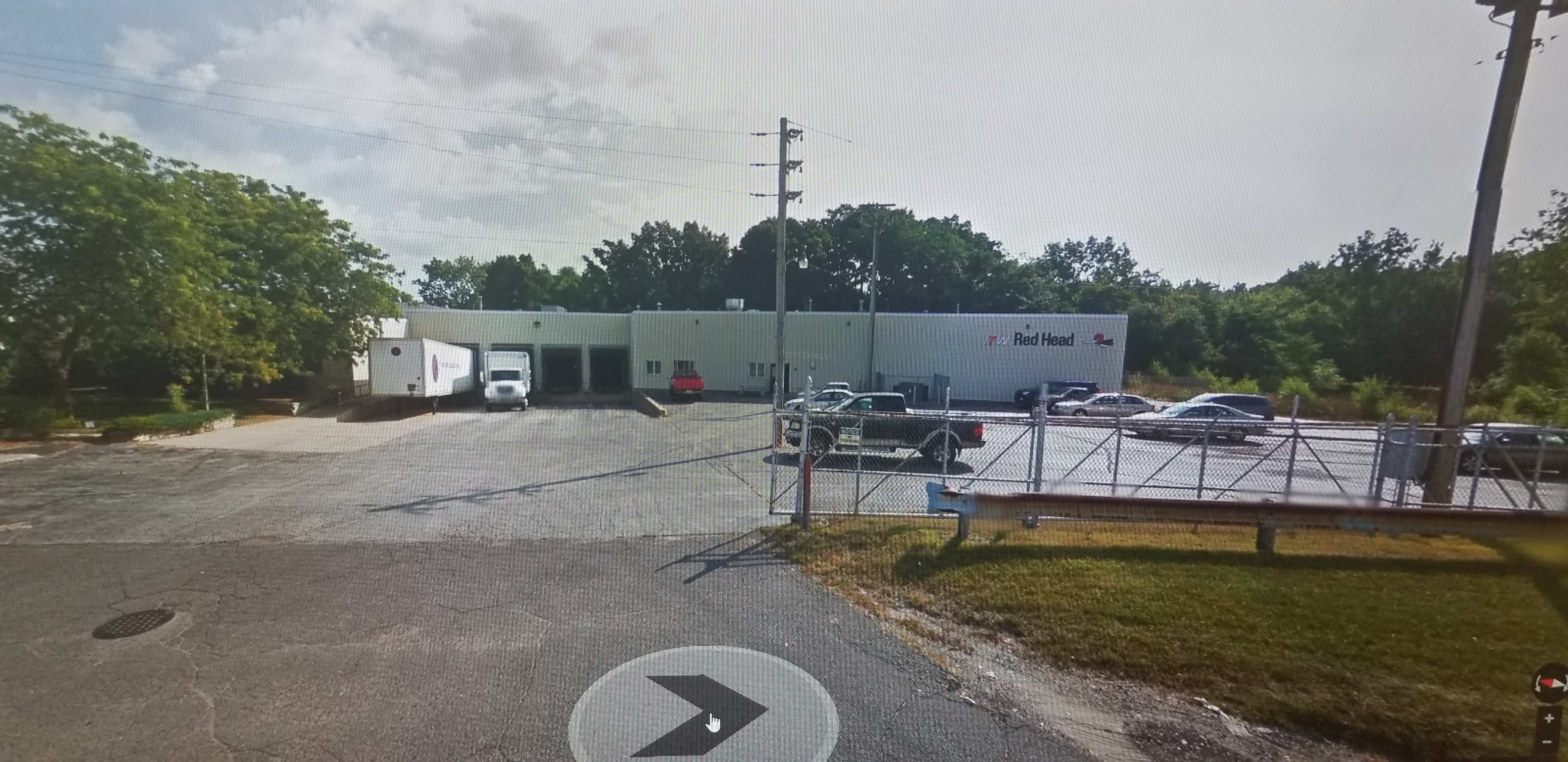 A commercial building with the name "Red Head" displayed, surrounded by vehicles parked outside on a paved lot.