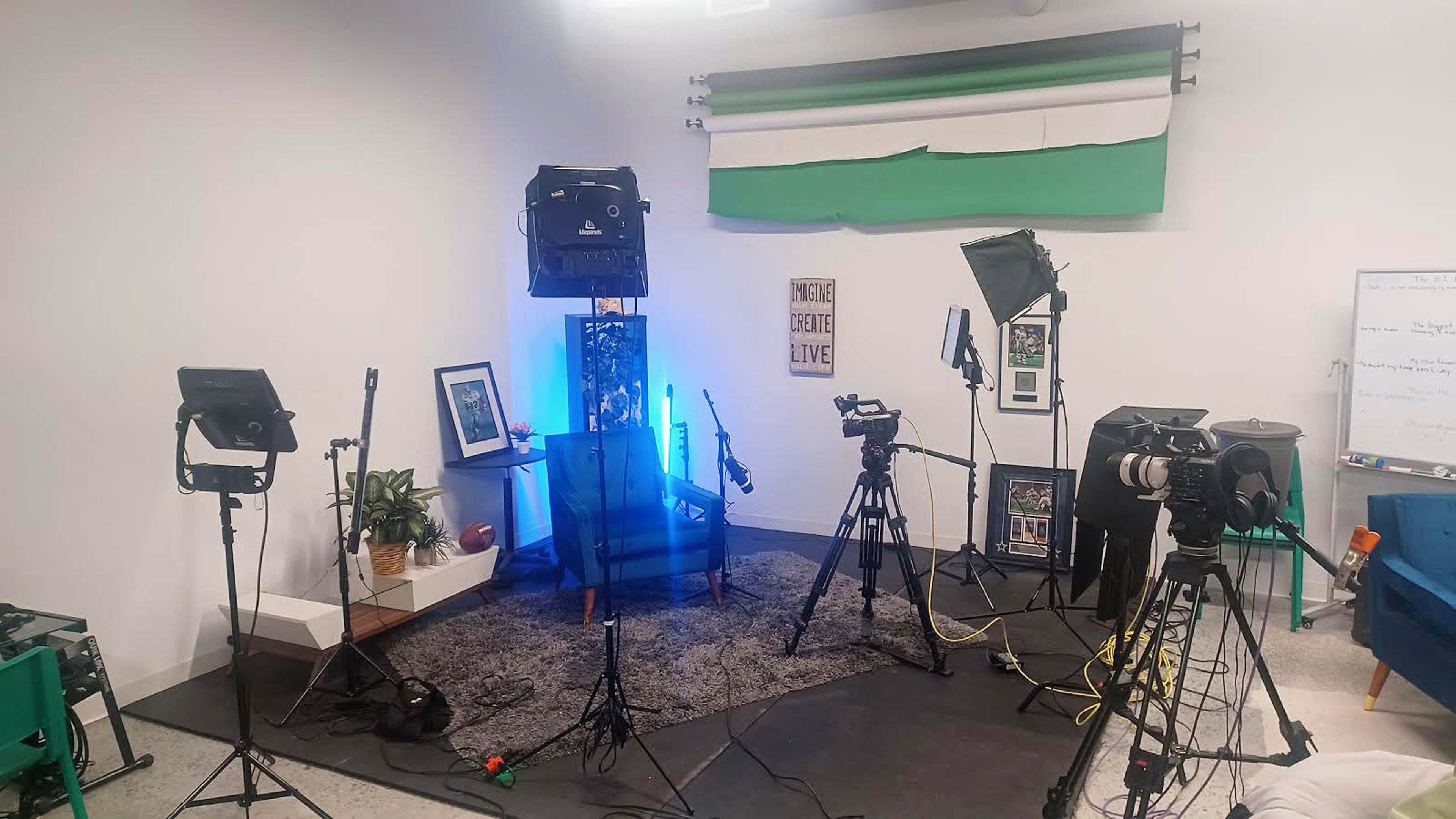 A studio setup with multiple cameras, lighting equipment, and a backdrop, all arranged on a carpeted floor.