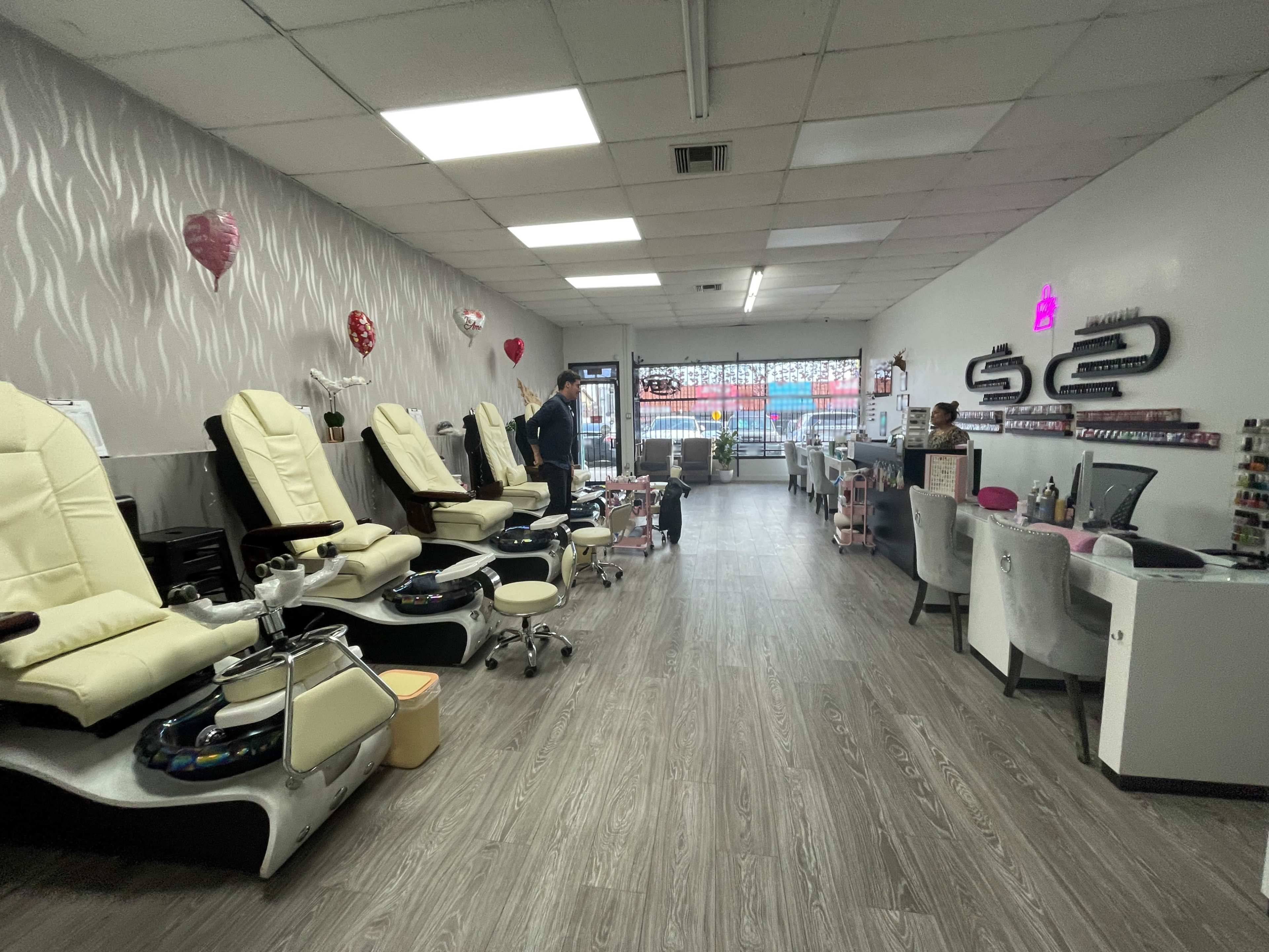 The interior of a nail salon features several pedicure chairs, a manicure station, and a reception area, all arranged in a spacious layout.