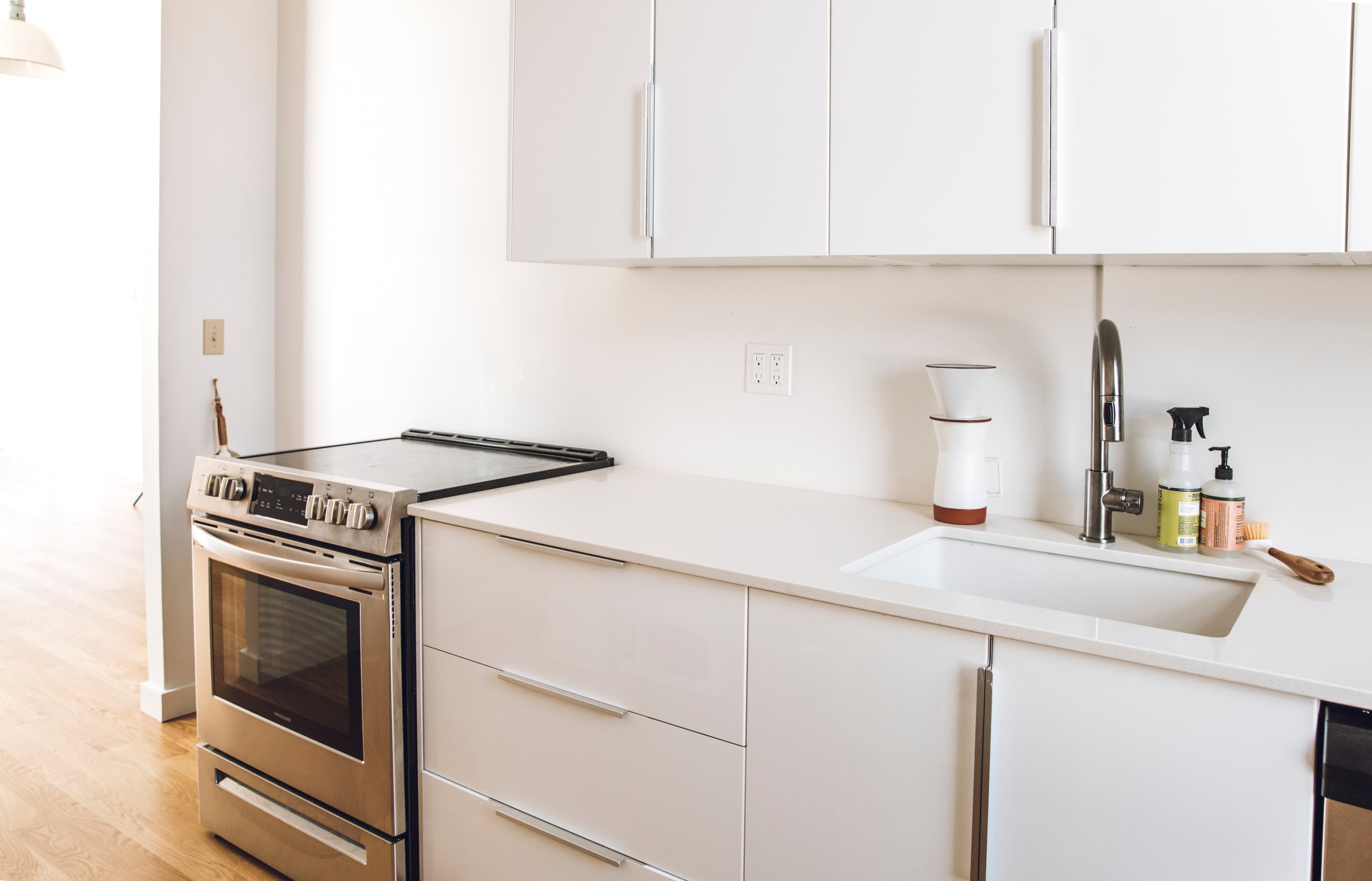 A modern kitchen featuring a stainless steel stove, a sleek sink, and minimalist cabinetry.